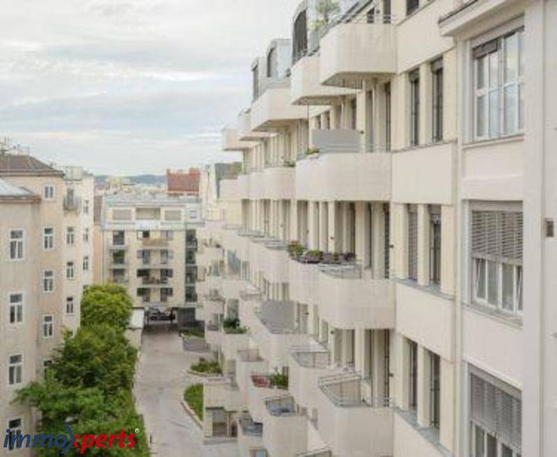 Fassade eines modernen Wohngebäudes mit zahlreichen Balkonen und urbaner Umgebung.