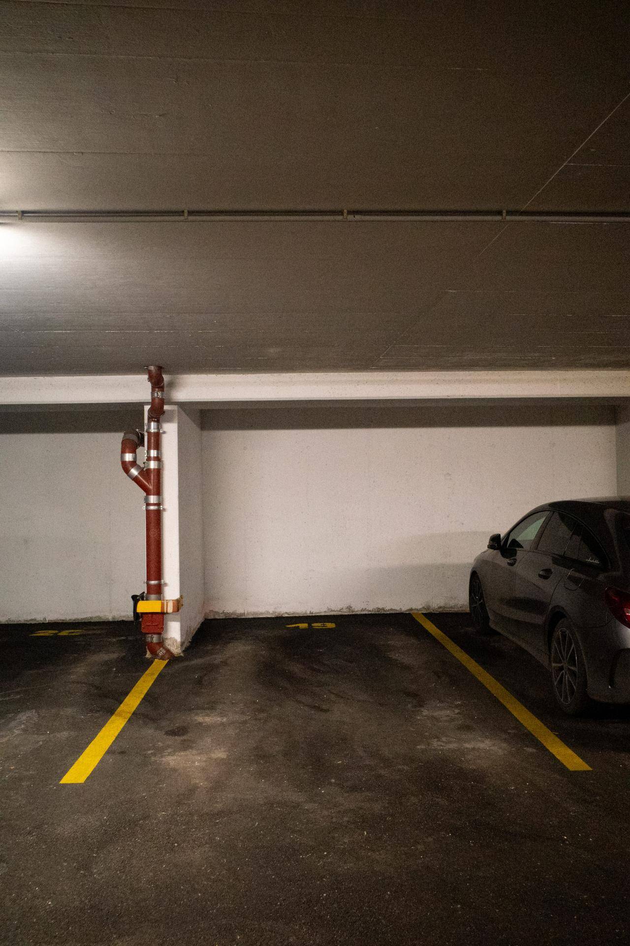 Einzelner Tiefgaragenstellplatz mit gelben Markierungen und einem geparkten Fahrzeug.