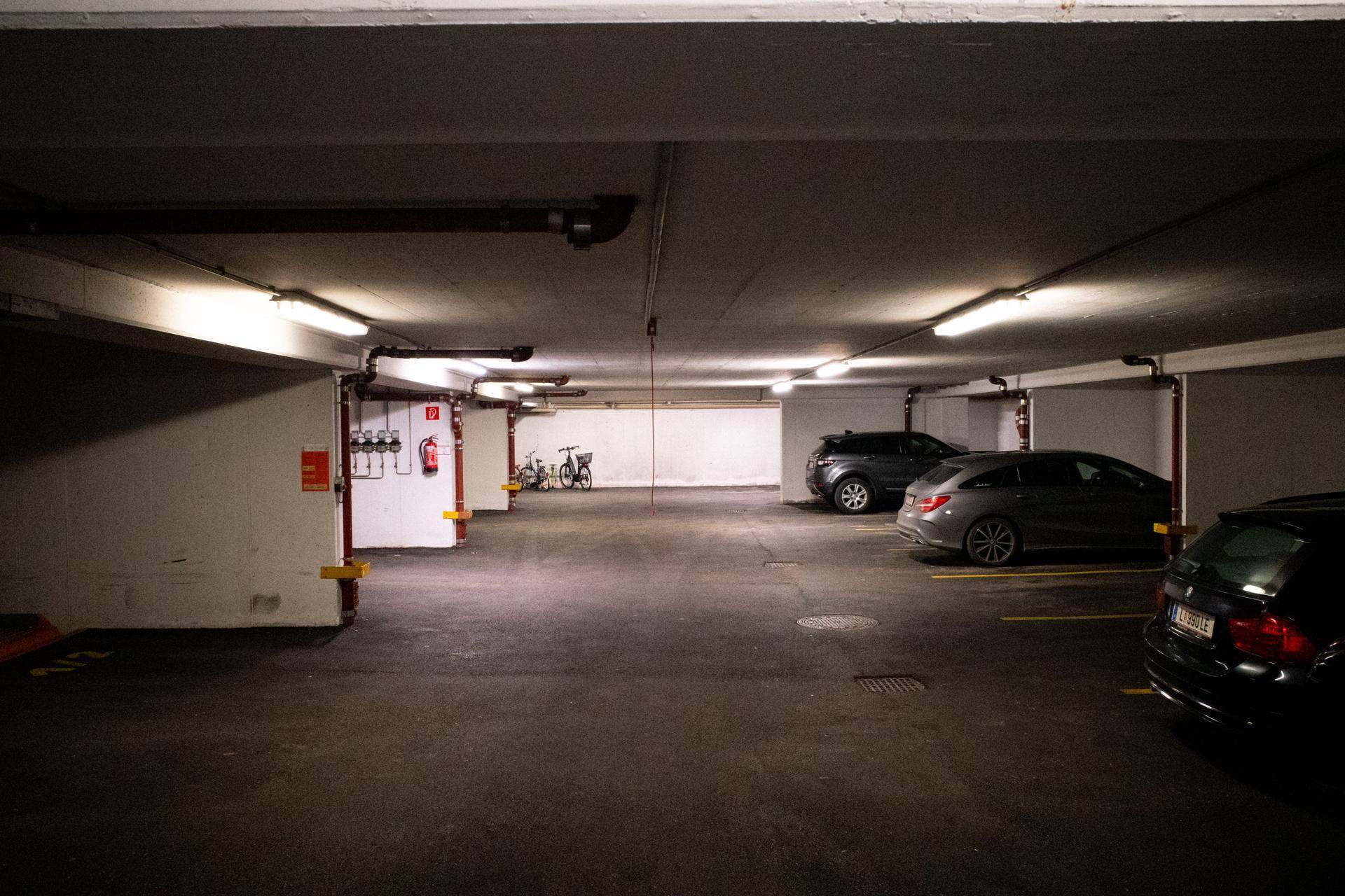 Geräumige Tiefgarage mit vielen Stellplätzen, einigen Fahrzeugen und einem Fahrrad.