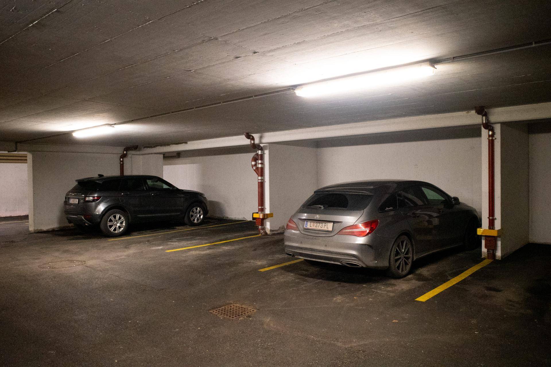 Geräumige Tiefgarage mit mehreren Stellplätzen und zwei geparkten Fahrzeugen.