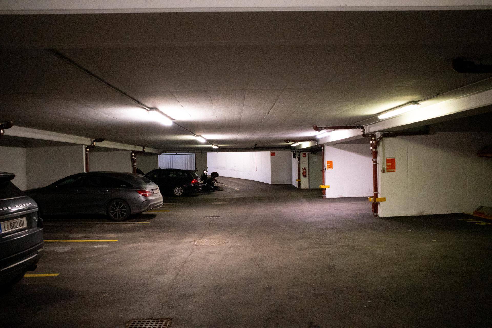 Weitläufige Tiefgarage mit zahlreichen Stellplätzen und Zufahrt im Hintergrund.