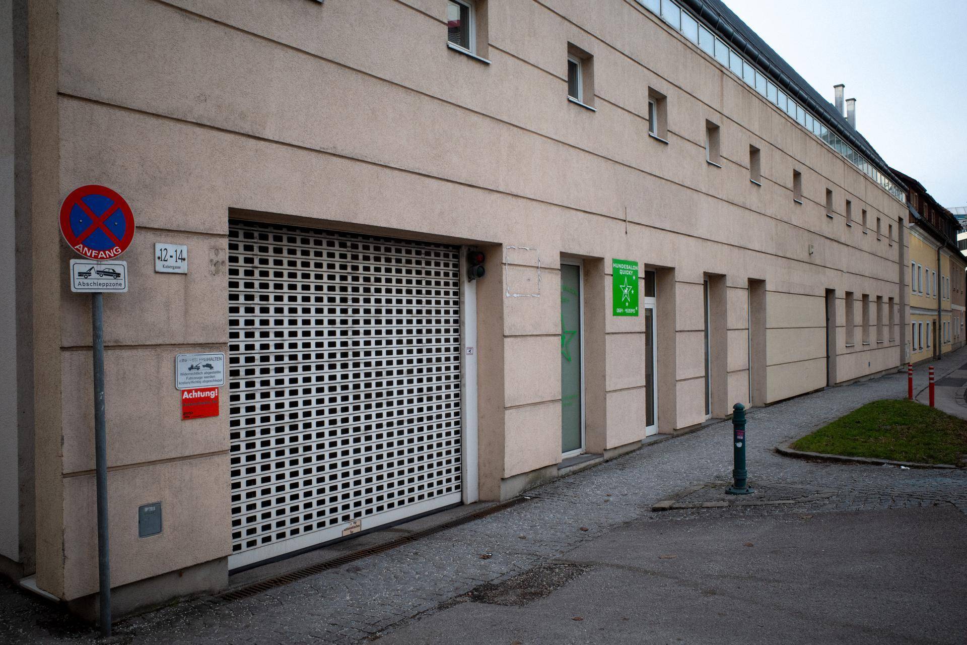 Gebäudefassade mit großem Rolltor zur Tiefgarage und kleinen Fenstern.