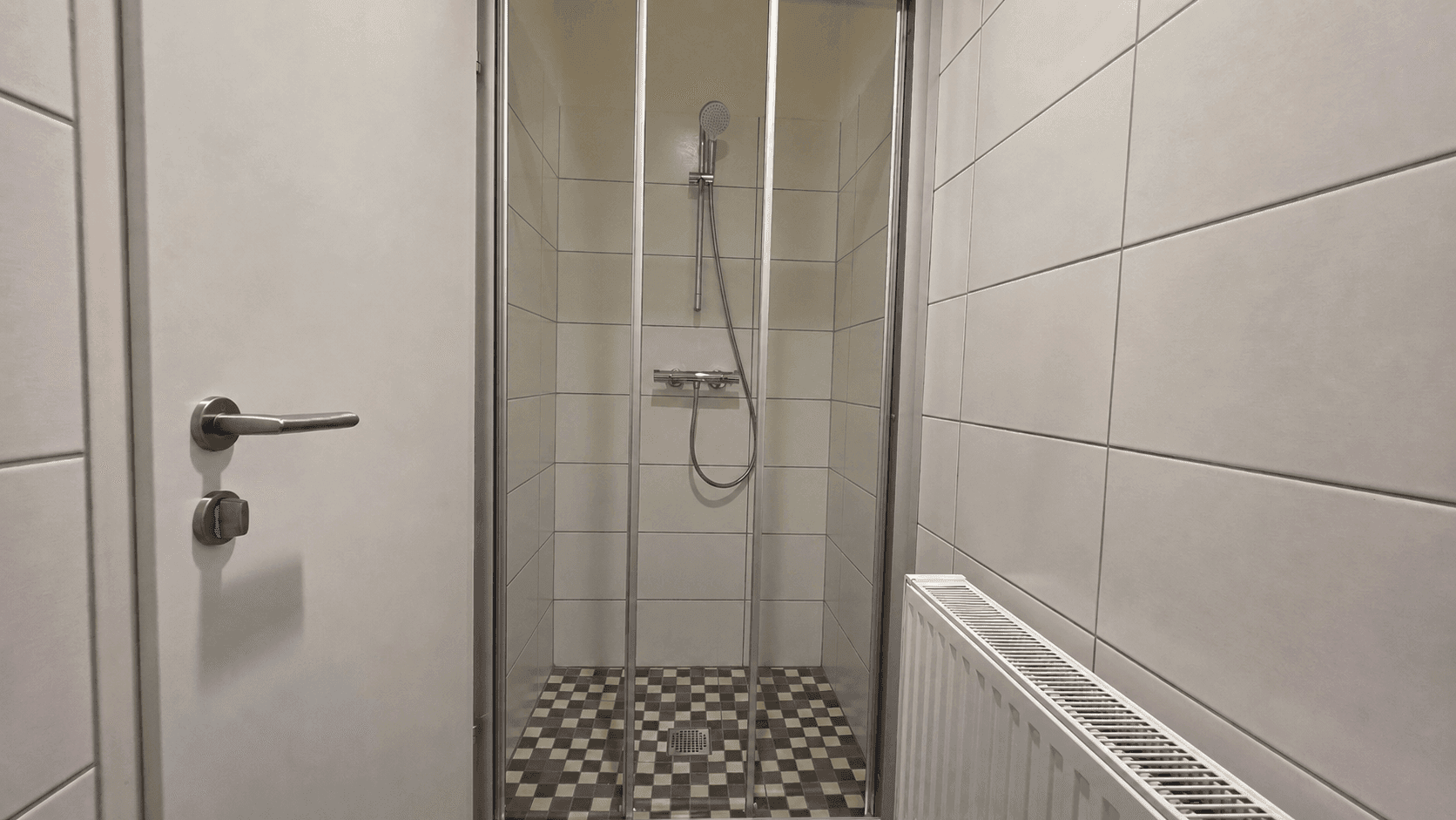Duschbereich mit Glasabtrennung und gemusterten Bodenfliesen, sauber und funktional gestaltet.