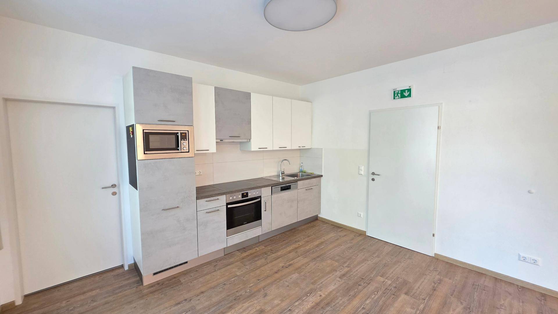 Funktionale Einbauküche mit modernen Geräten, hellen Schränken und praktischem Laminatboden.