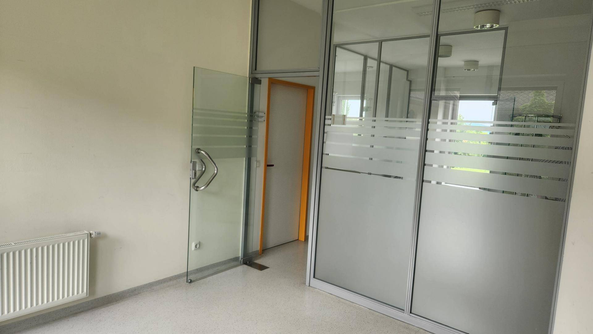 Moderner Bürobereich mit Glaswänden und einem Heizkörper, der für angenehme Temperaturen sorgt.