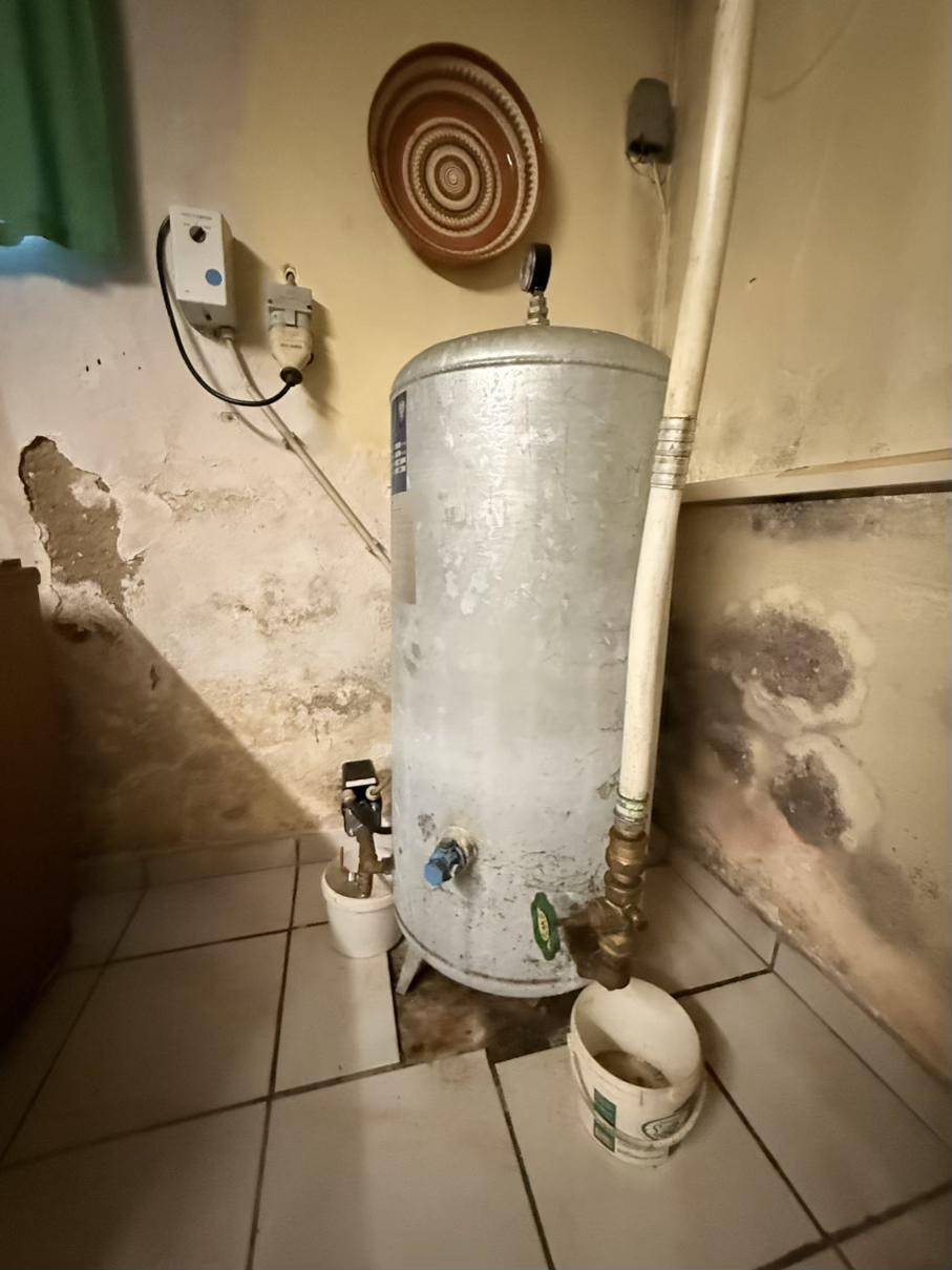 Warmwasserspeicher oder Boiler in einem Hauswirtschaftsraum mit gefliestem Boden.