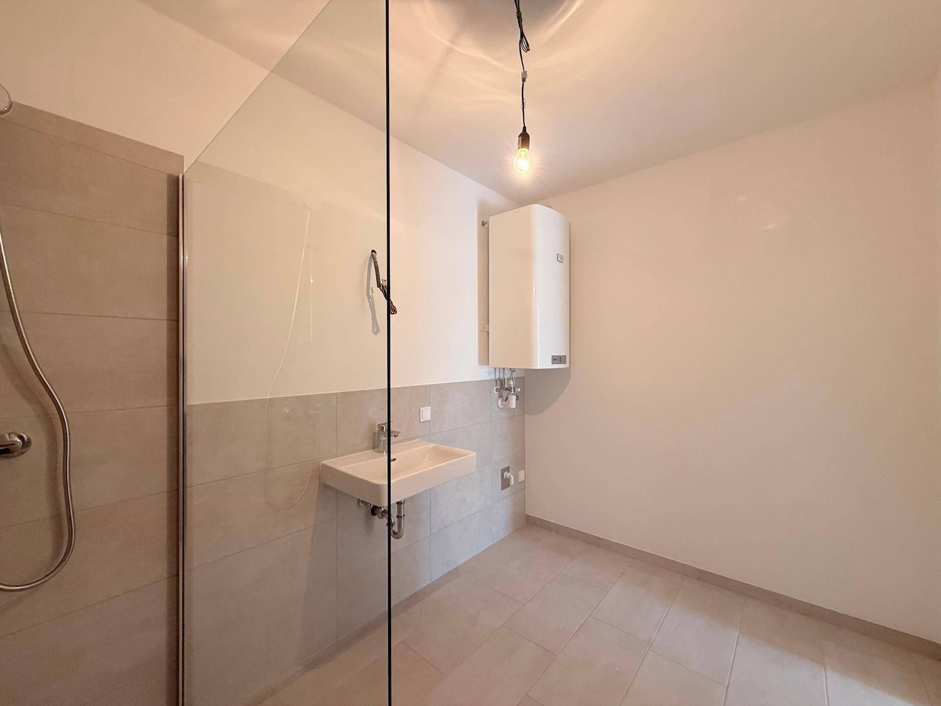 Helles Badezimmer mit begehbarer Dusche, Waschbecken und Warmwasserboiler.