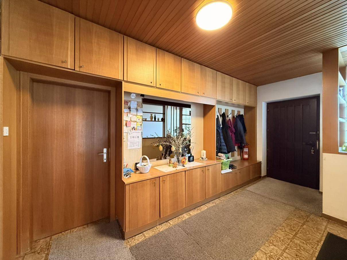 Flur mit Holzdeckenverkleidung, Einbauschränken und gemusterten Fliesen auf dem Boden.