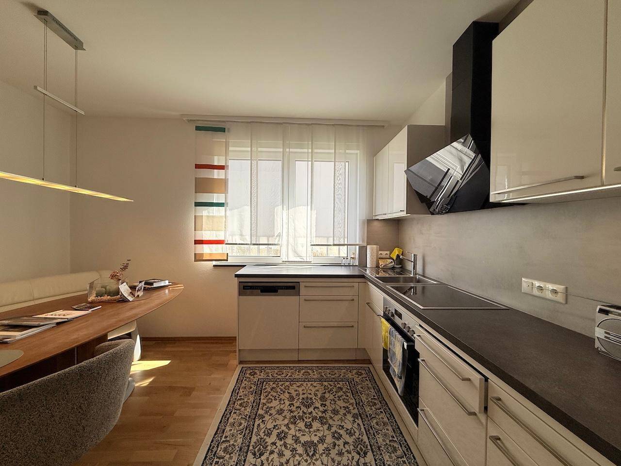 Moderne Küche mit Essbereich, Fenster und Holzboden, hell und funktional gestaltet.