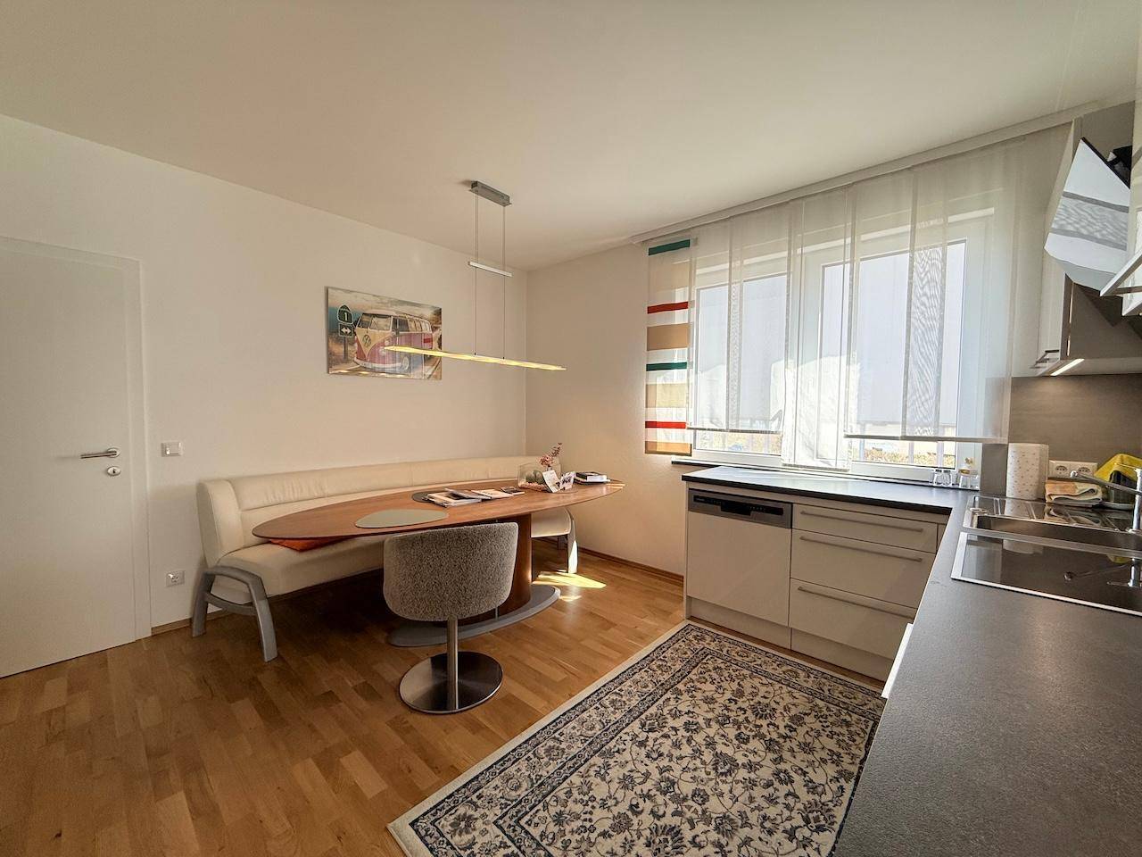 Helle Küche mit Essbereich, Holzboden und modernen Geräten, ideal für Familien.