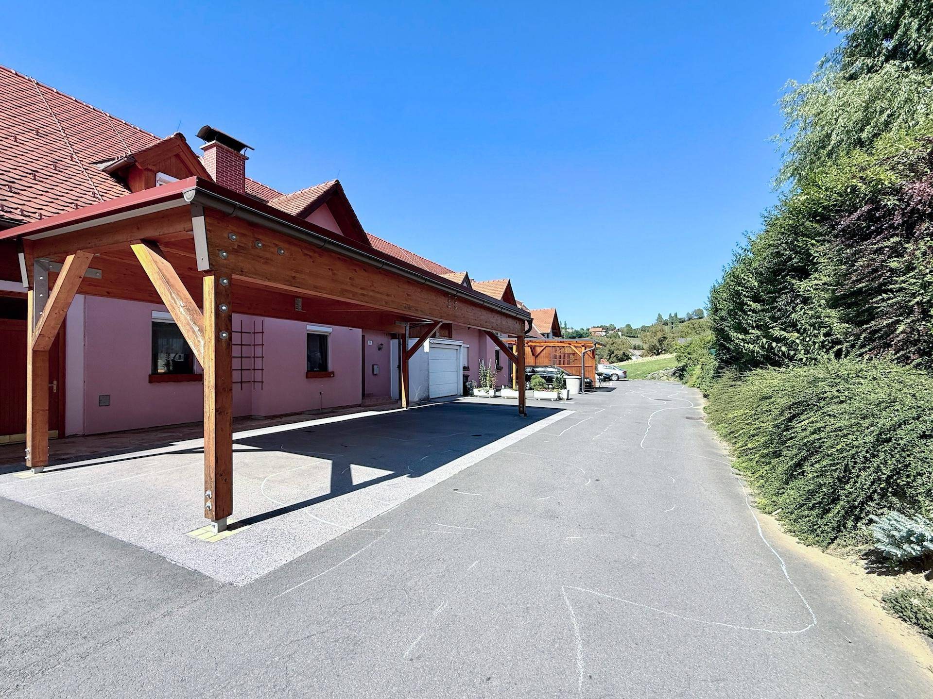 Vorderansicht des Hauses mit großem Carport und langer Auffahrt unter blauem Himmel.