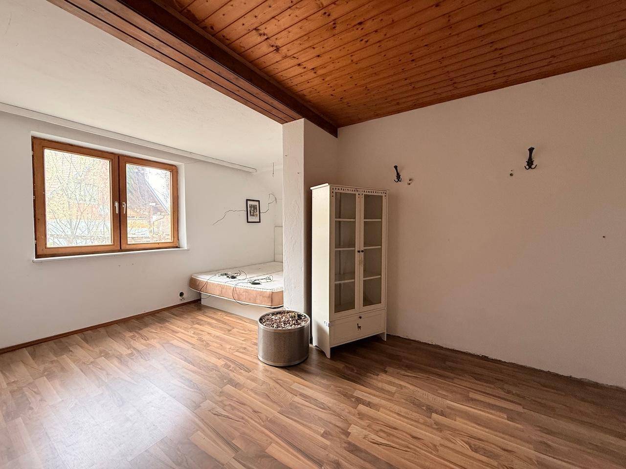 Schlafzimmer mit Holzbalken, Holzdecke und Laminatboden, bietet eine gemütliche Atmosphäre.