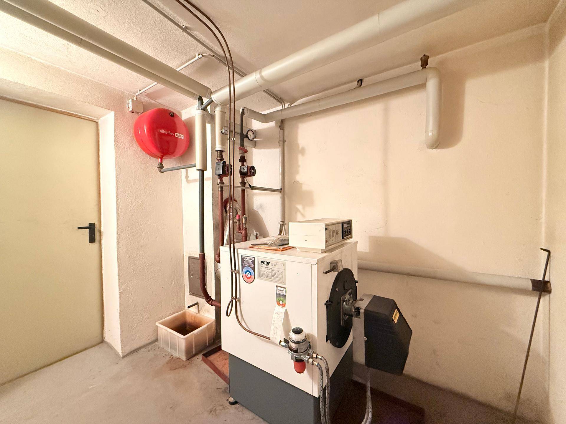Heizungsraum im Keller mit zentraler Heizanlage und sichtbaren Rohrleitungen.