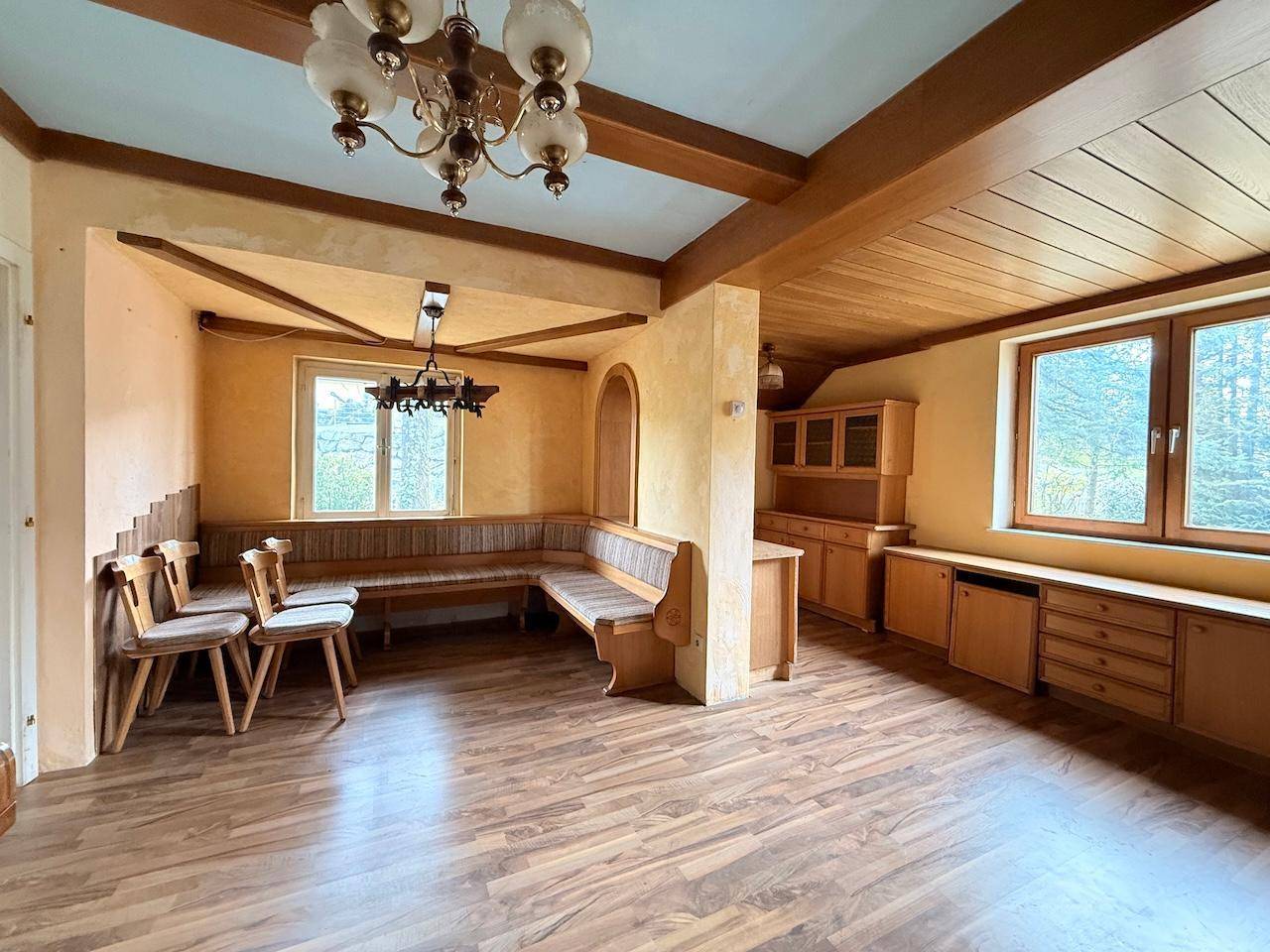 Wohn-Essbereich mit Holzbalken, eingebauter Sitzbank und Holzmöbeln im traditionellen Stil.