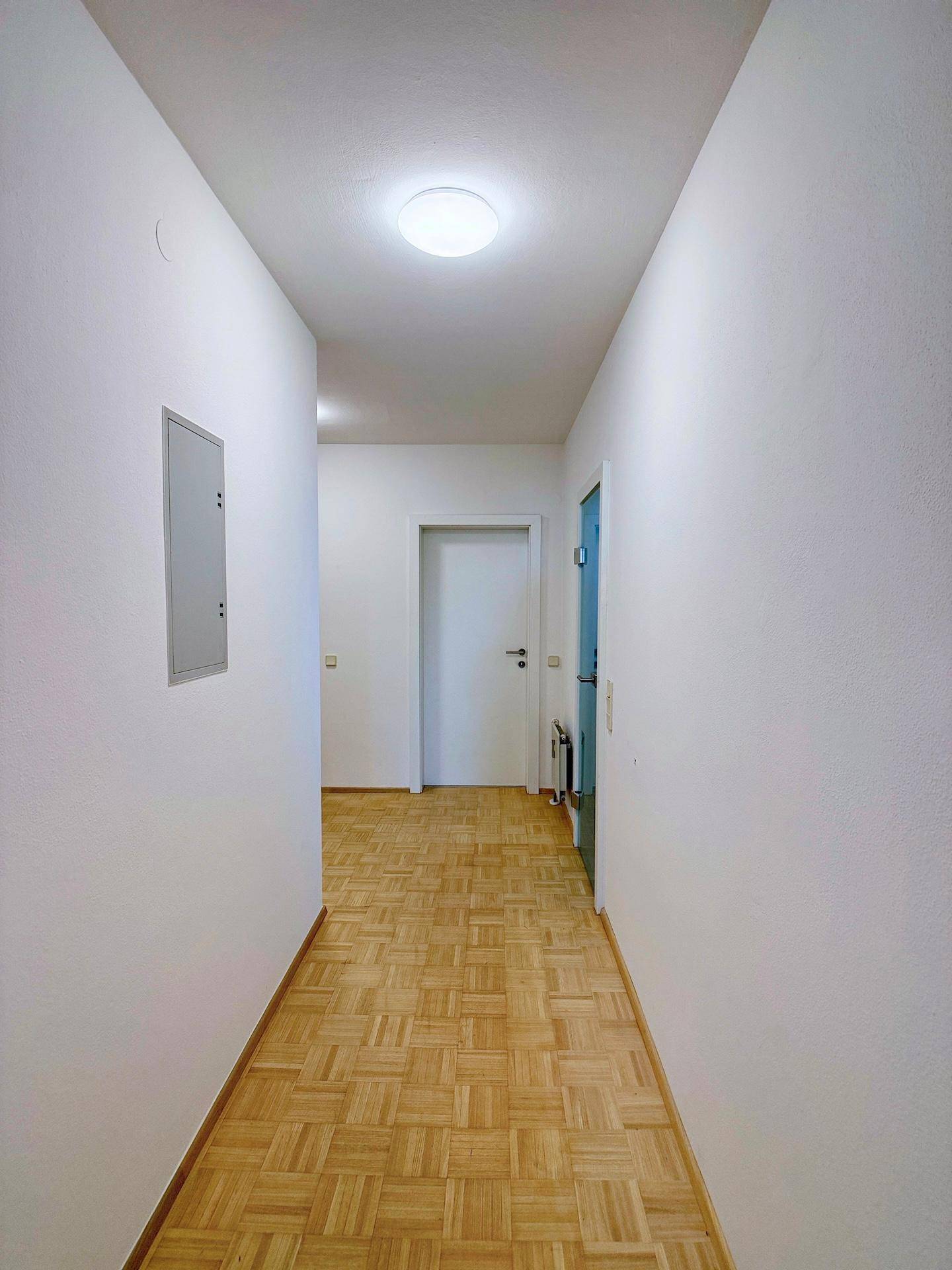 Heller Flur mit Parkettboden, der zu den verschiedenen Zimmern der Wohnung führt.