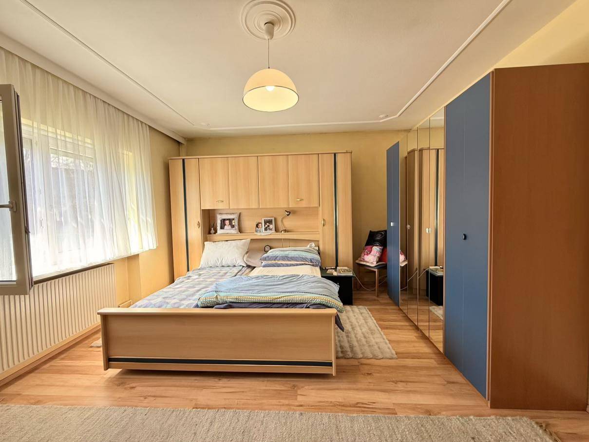 Schlafzimmer mit Doppelbett, Einbauschrank und einem Fenster, das Tageslicht hereinlässt.