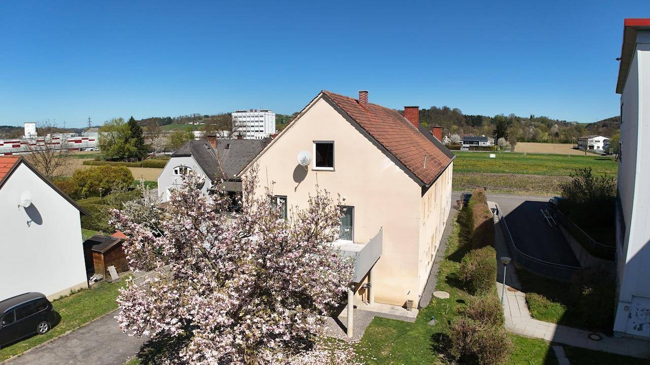 Luftaufnahme des Hauses mit Garten, Balkon und ländlicher Umgebung unter blauem Himmel.