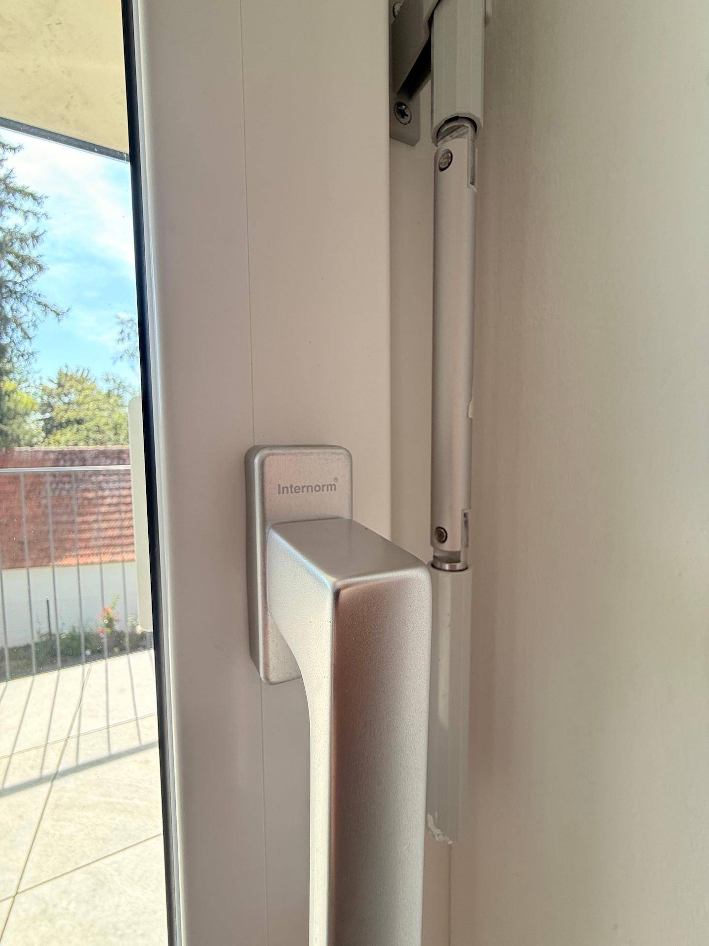Detailaufnahme eines modernen Fenstergriffs mit Blick nach draußen.