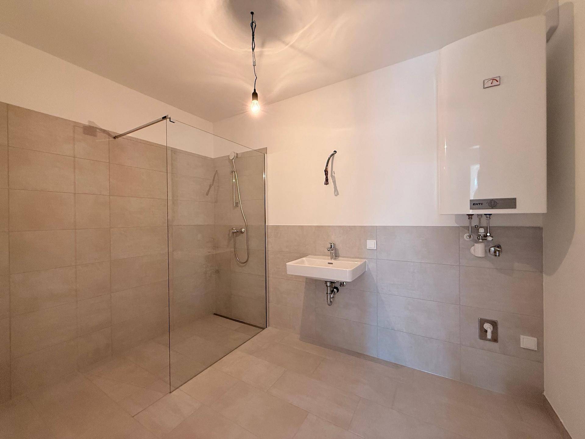 Geräumiges Badezimmer mit begehbarer Dusche, Waschbecken und Warmwasserboiler.