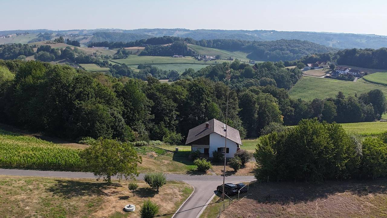 Freistehendes Haus in idyllischer Hügellandschaft mit weitem Blick über grüne Felder und Wälder.