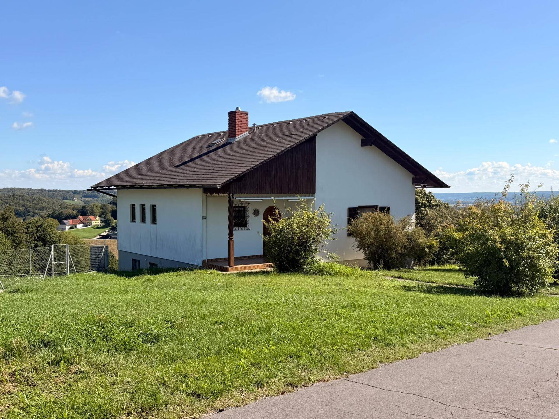 Haus in idyllischer Hanglage mit weitem Blick über die umliegende Landschaft und viel Grünfläche.