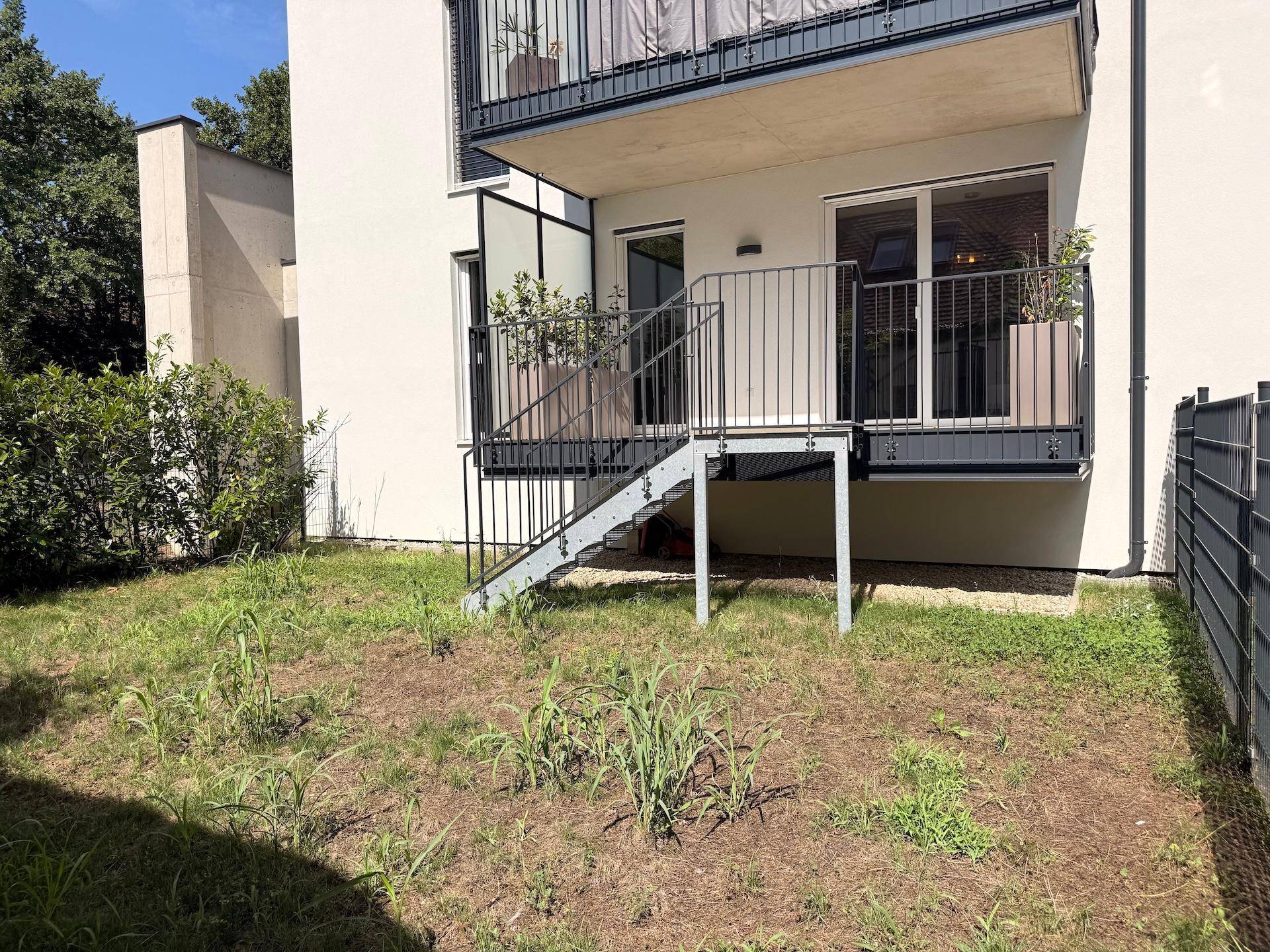Erdgeschossbalkon mit Zugang zum Gartenbereich und Blick auf die umgebende Vegetation.