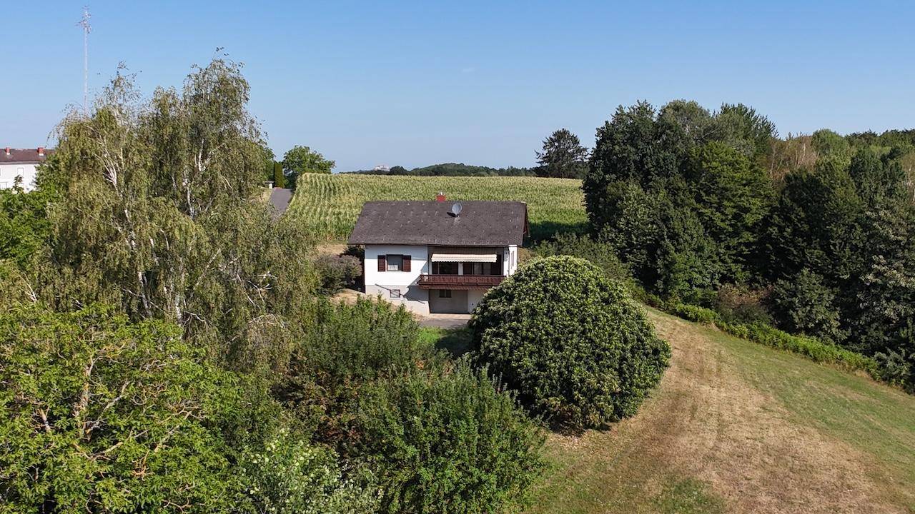 Das Haus liegt idyllisch zwischen Bäumen und Feldern, umgeben von unberührter Natur.