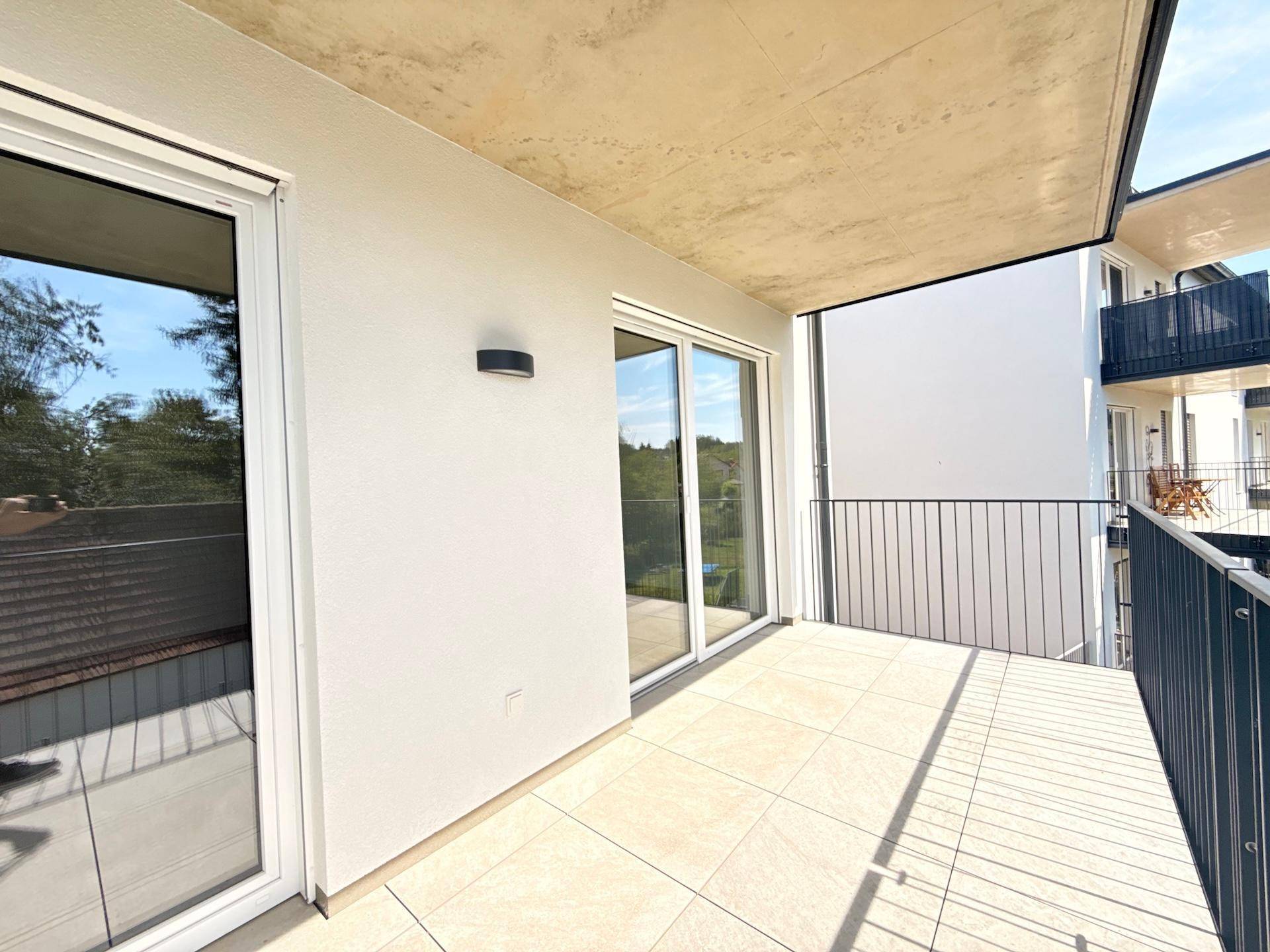 Geräumiger Balkon mit Fliesenboden und Blick auf die umliegenden Gebäude.