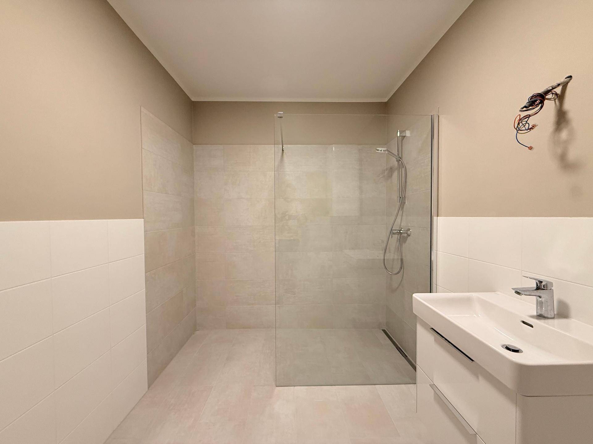 Helles Badezimmer mit großer, begehbarer Dusche und modernem Waschbecken.