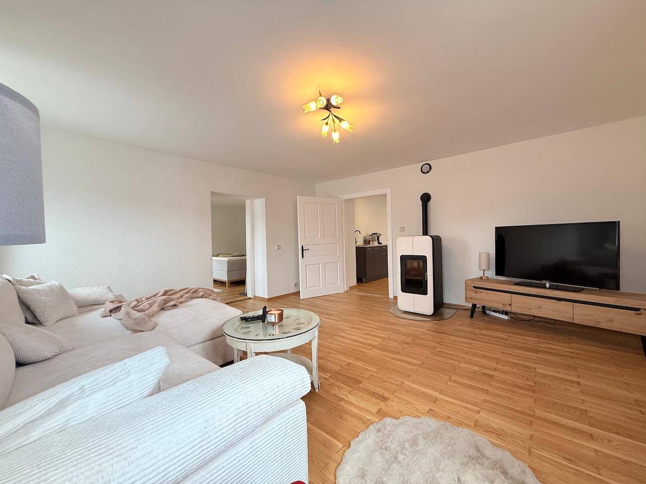 Gemütliches Wohnzimmer mit modernem Kaminofen, Fernseher und Holzboden.