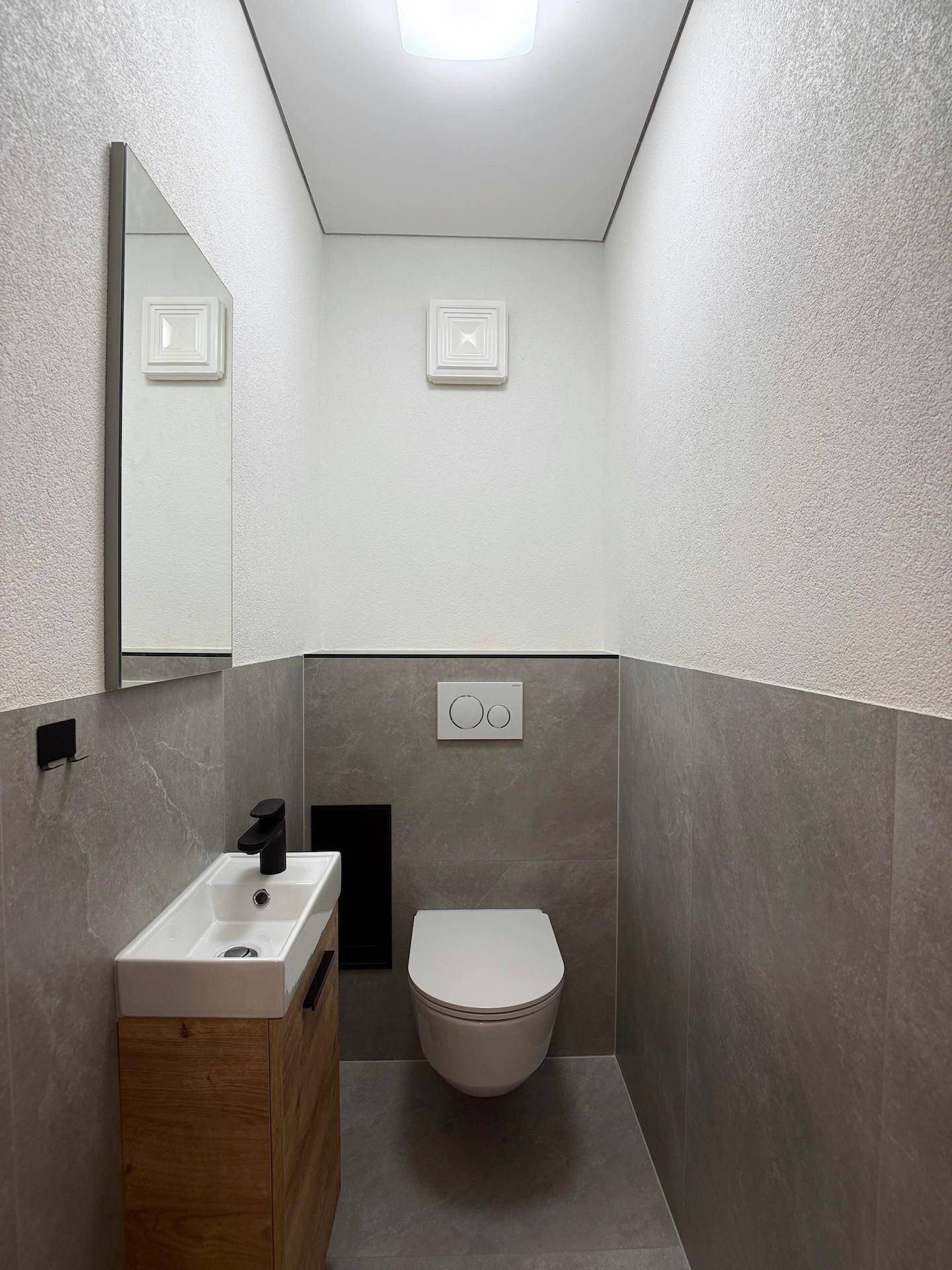 Separates Gäste-WC mit modernem Waschtisch und wandhängender Toilette in schlichtem Design.