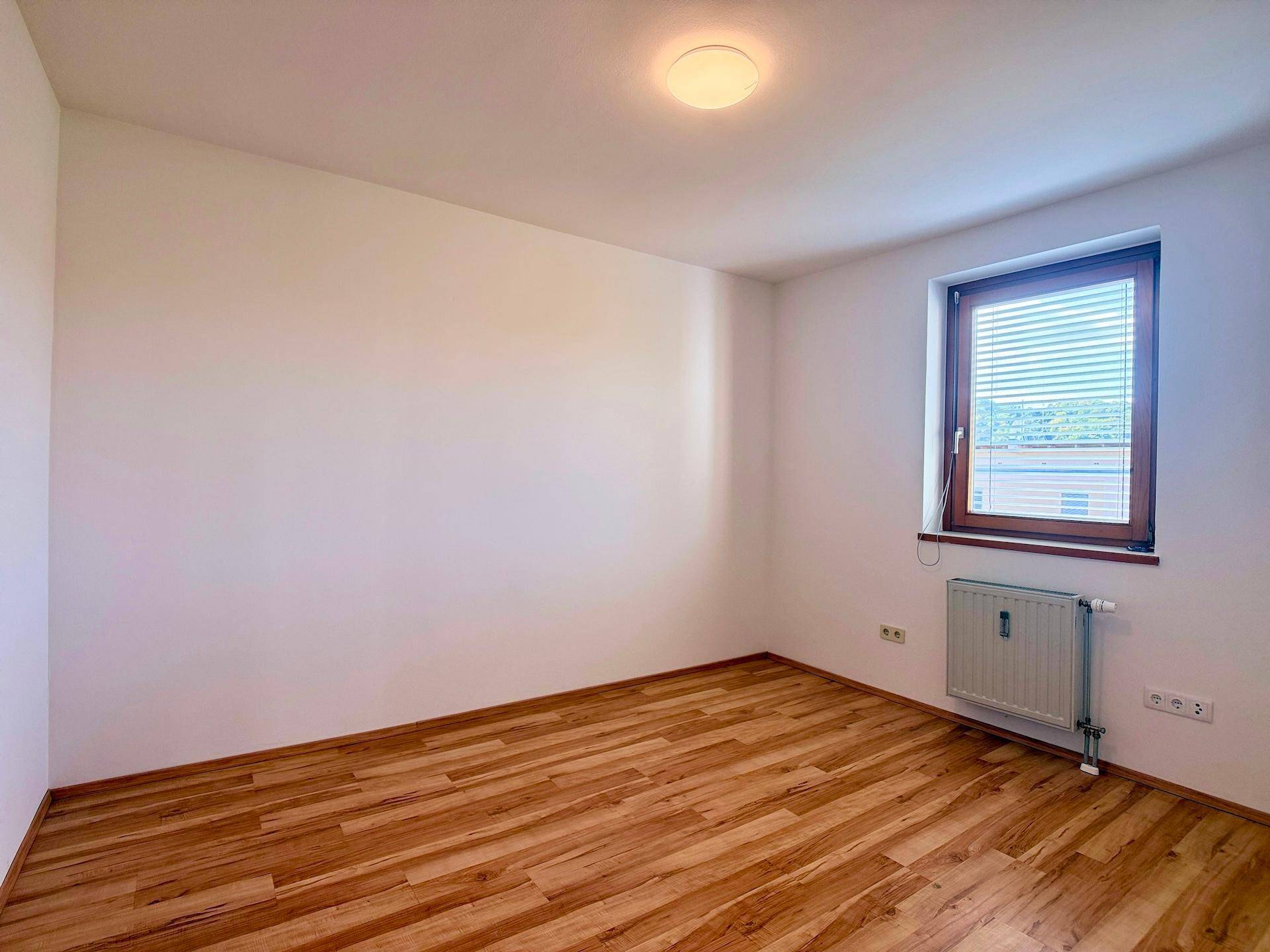 Geräumiges Schlafzimmer mit neuwertigem Laminatboden, bereit zur individuellen Einrichtung.