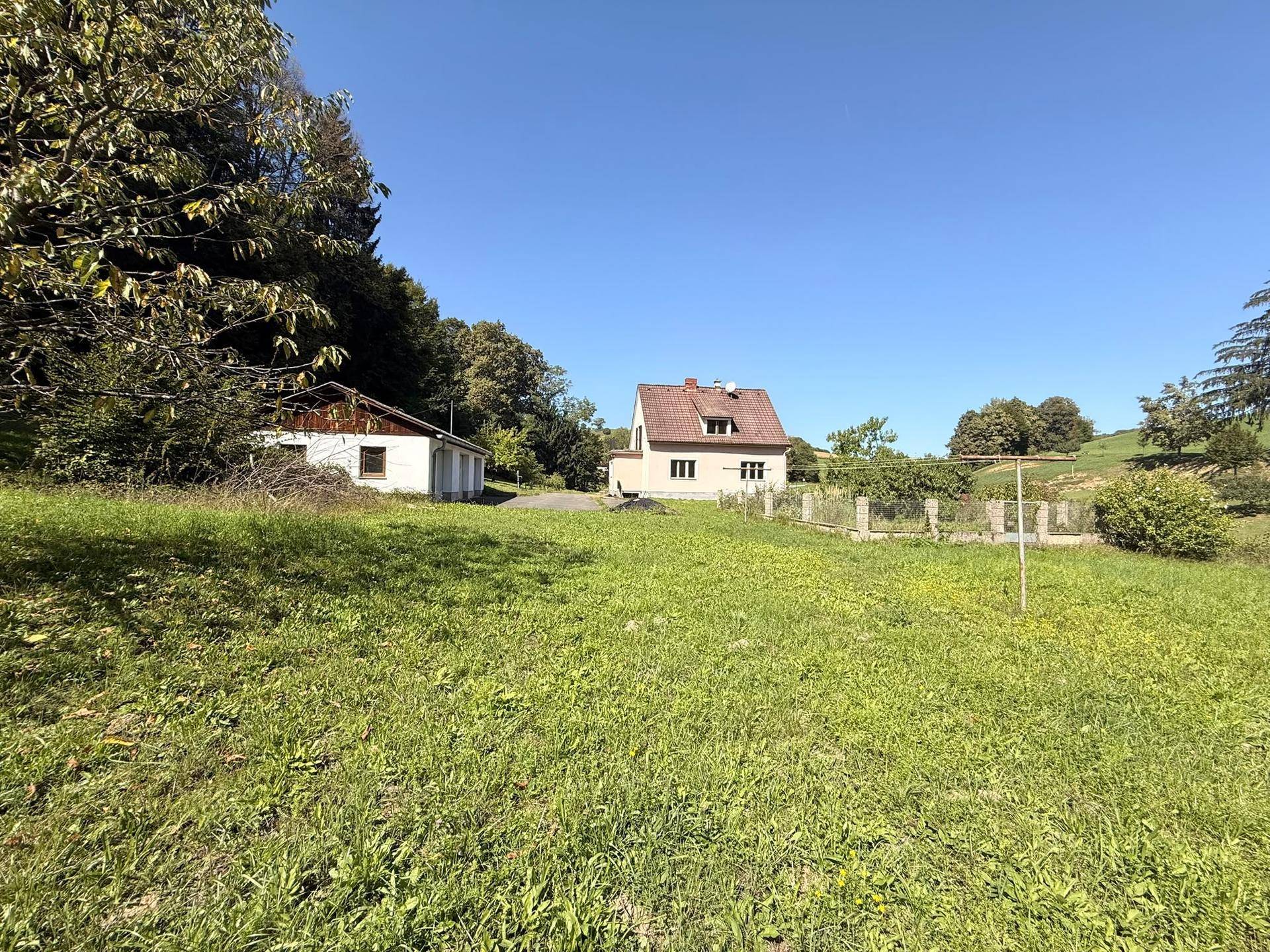 Weitläufiges Grundstück mit Haupthaus und Nebengebäude, eingebettet in eine grüne Landschaft.