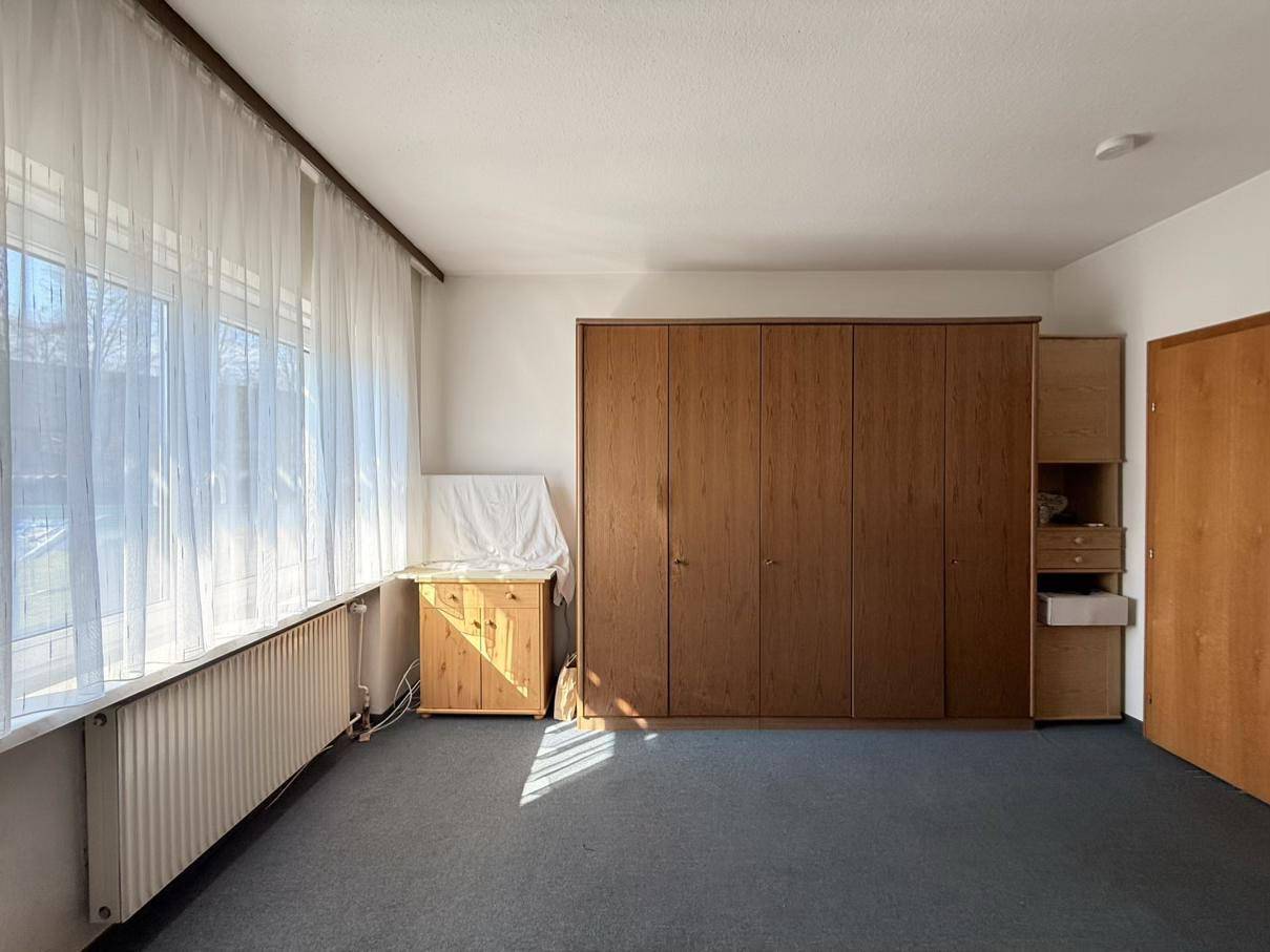 Helles Zimmer mit großem Einbauschrank und einem breiten Fenster, das viel Tageslicht bietet.
