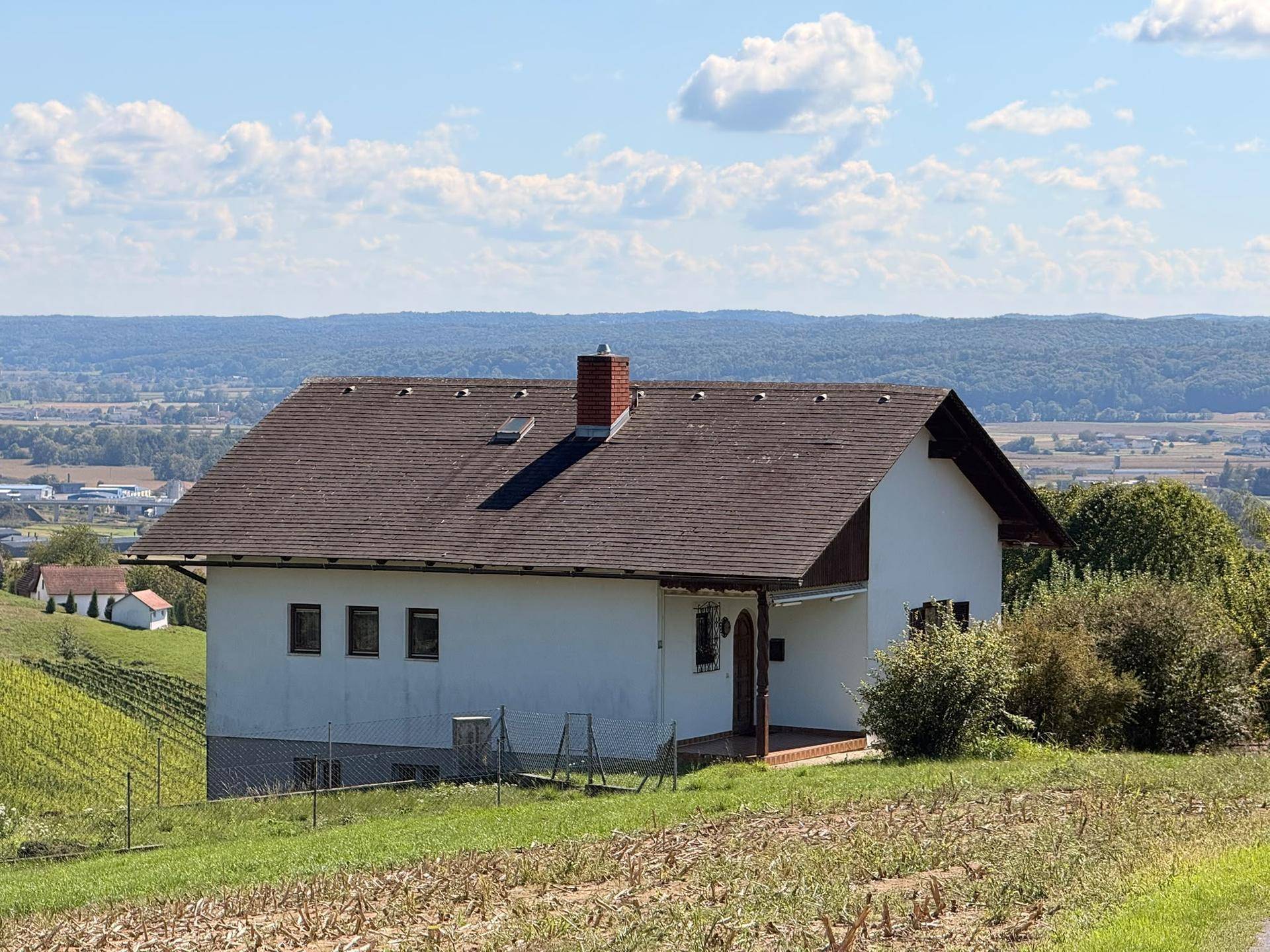 Haus in Hanglage mit weitem Blick über die umliegende Landschaft und angrenzende Weinberge.