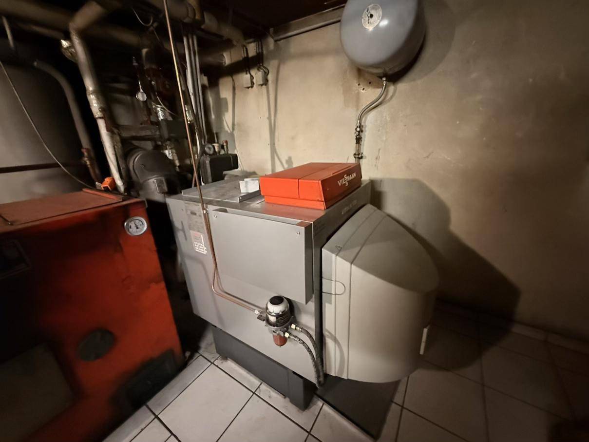 Heizraum mit einem modernen Heizsystem und zugehörigen Installationen auf gefliestem Boden.
