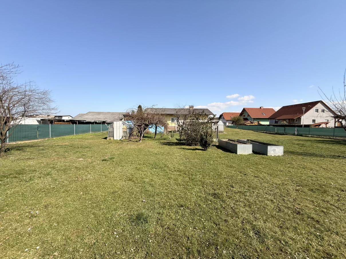 Großer Gartenbereich mit Hochbeeten und dem Haus im Hintergrund, umgeben von einer grünen Rasenfläche.