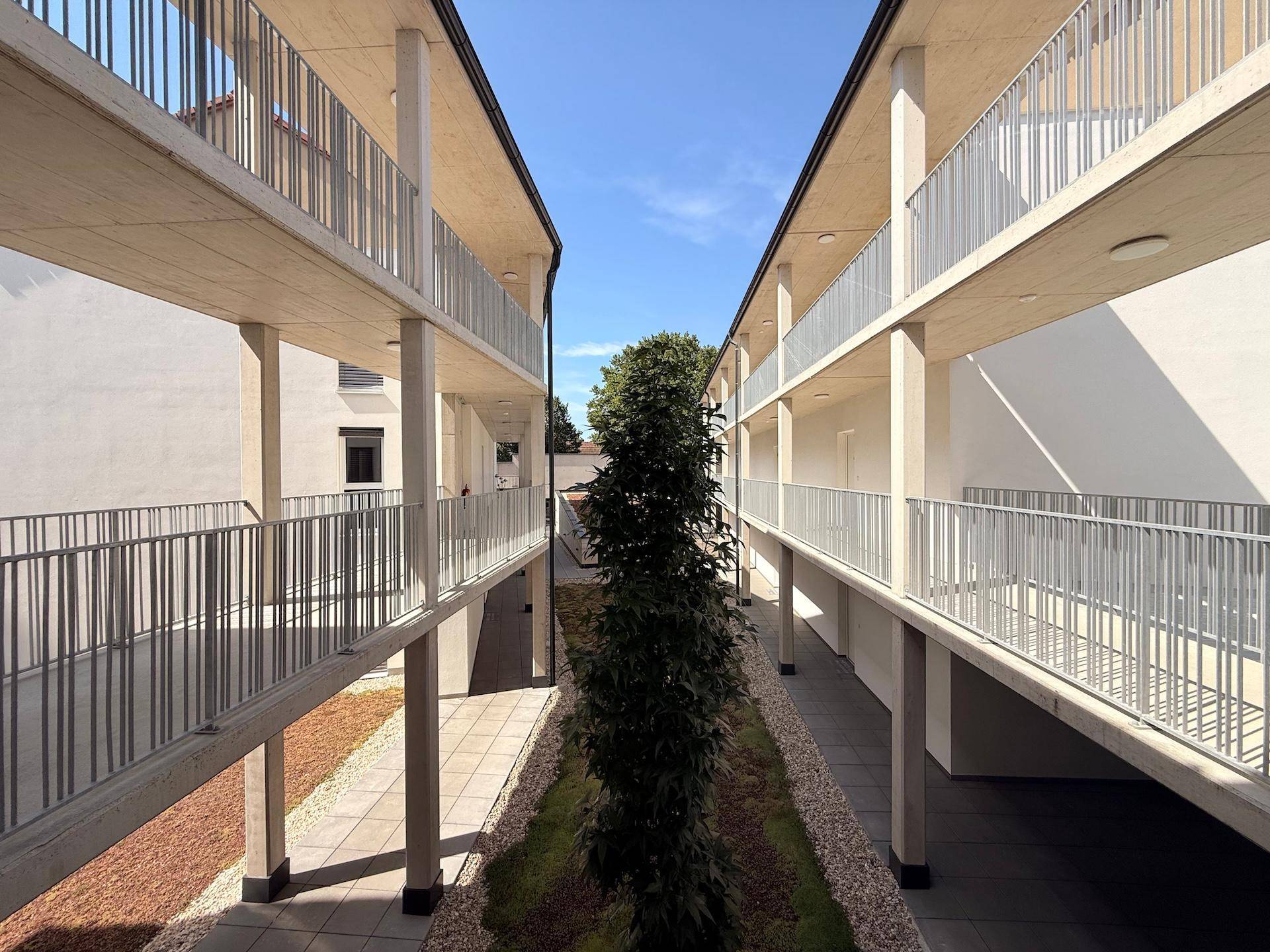 Blick in den begrünten Innenhof eines modernen Wohnkomplexes von einem oberen Stockwerk.