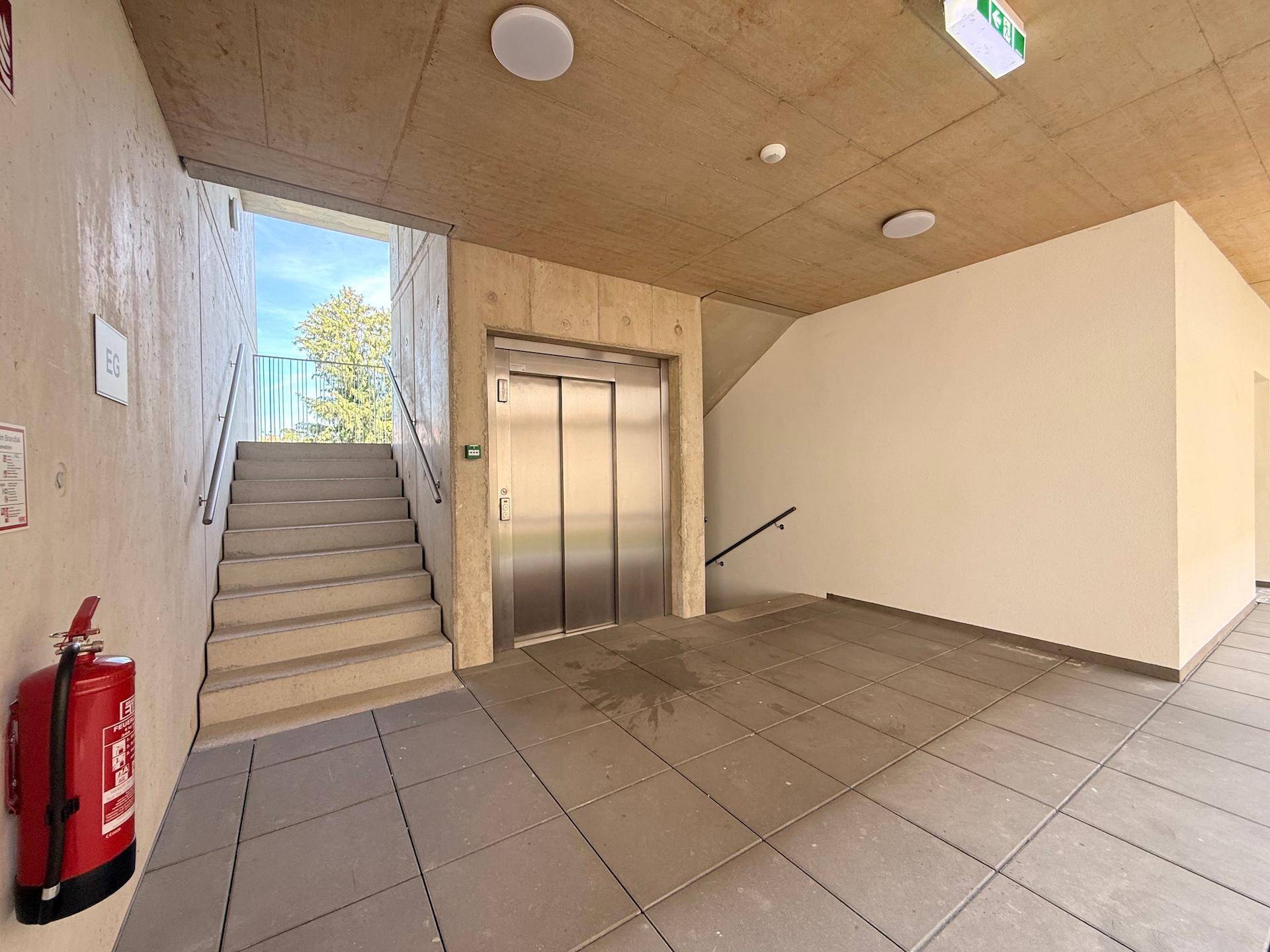 Eingangsbereich des Gebäudes mit Treppe, Aufzug und Brandschutzvorrichtung.