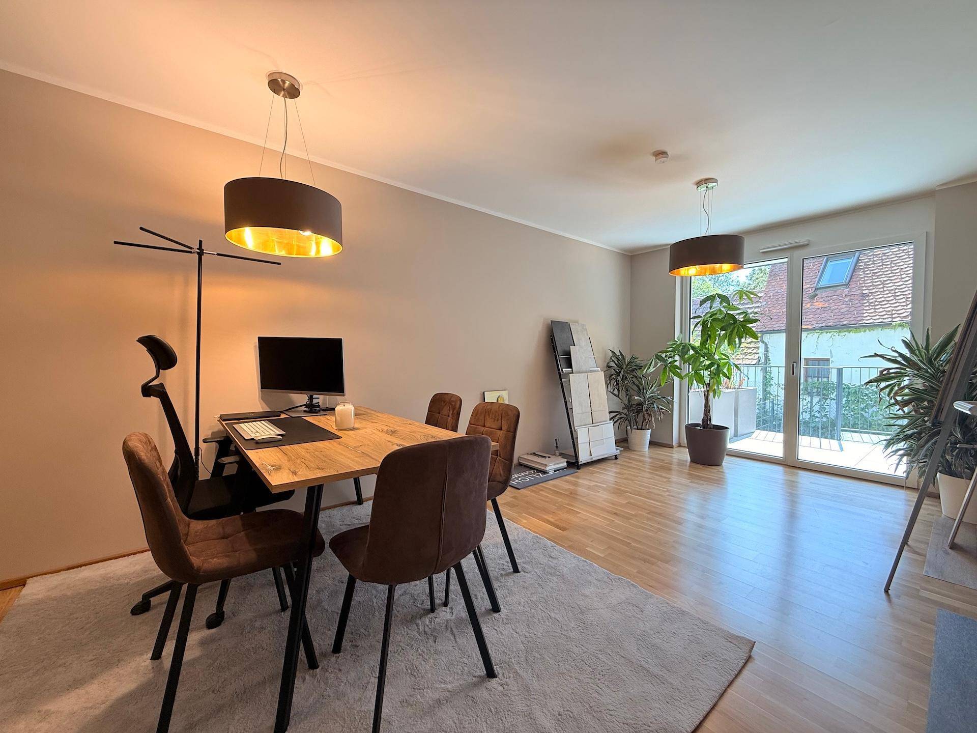 Heller Wohnbereich mit Esstisch, Pflanzen und Zugang zu einem Balkon.