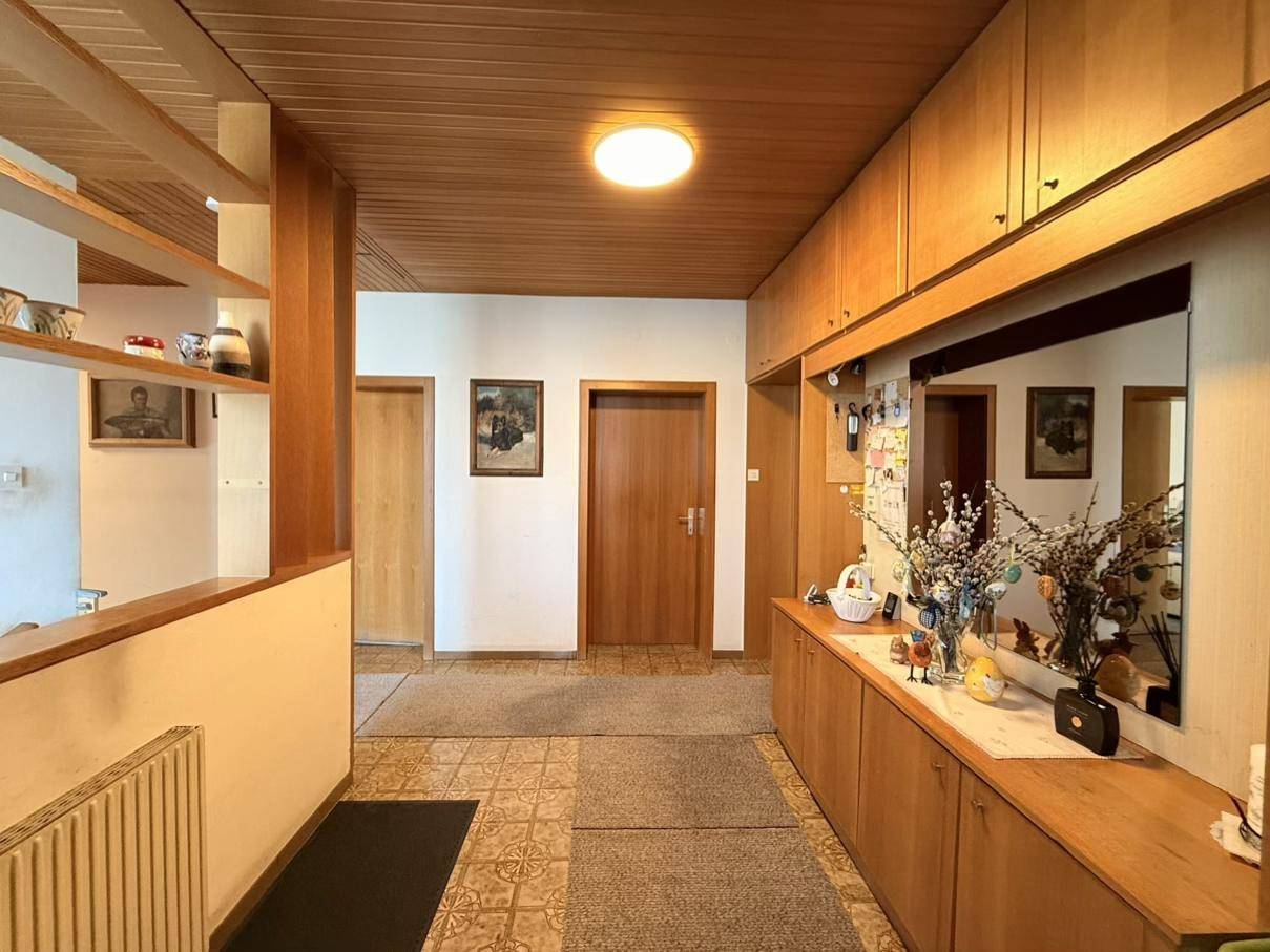 Flur mit Holzdeckenverkleidung, Einbauschränken und gemusterten Fliesen auf dem Boden.