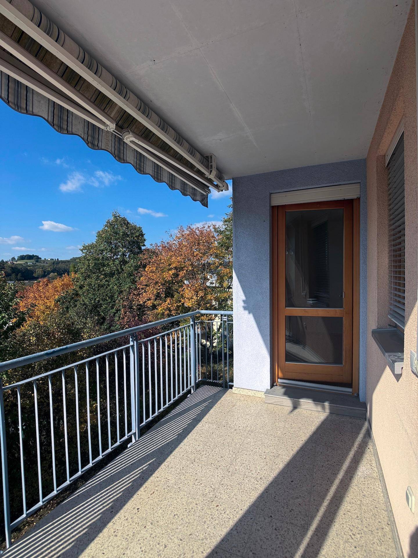 Sonniger Balkon mit Markise und weitem Blick ins Grüne, ideal zum Entspannen.