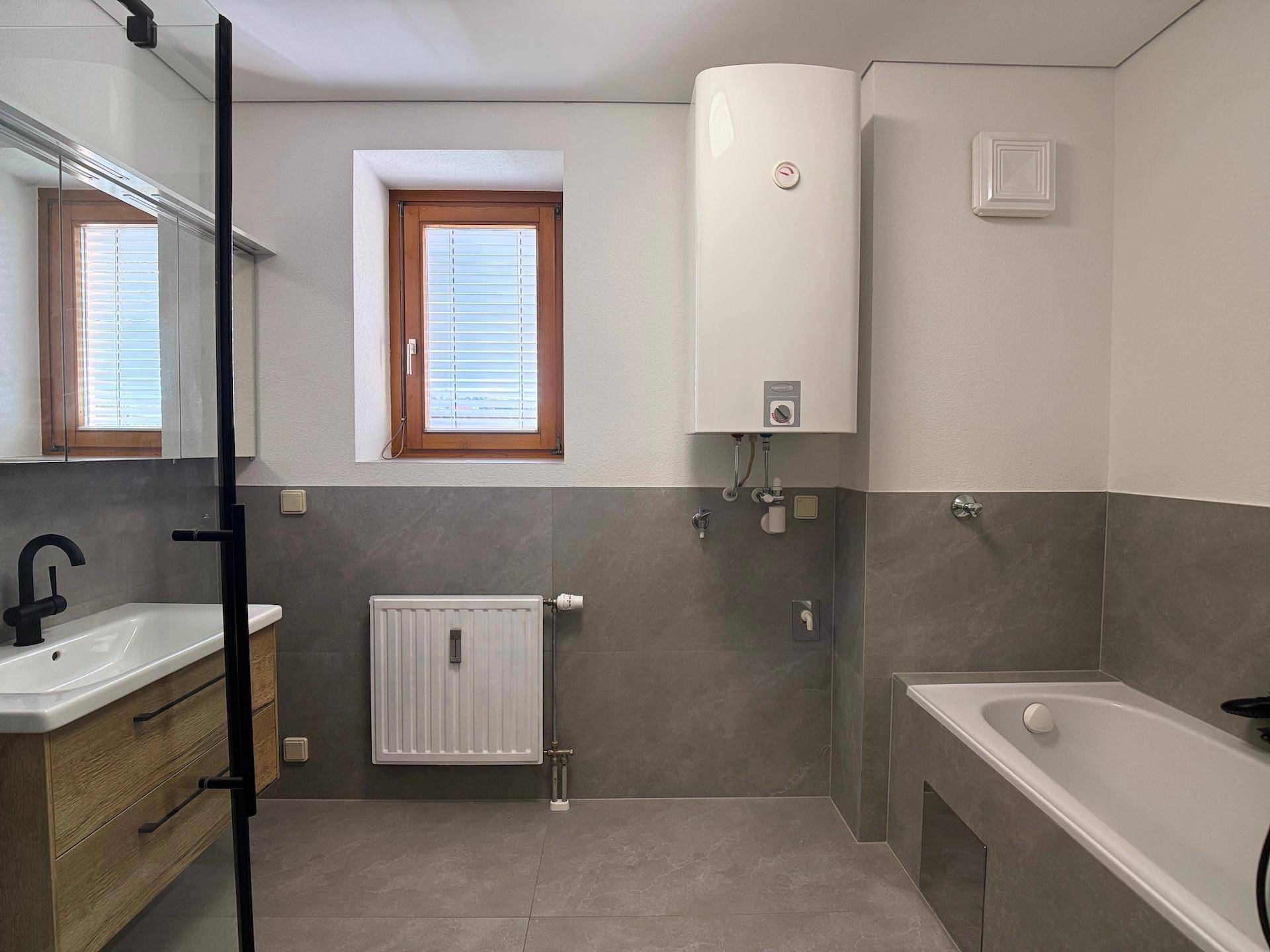 Komplettes Badezimmer mit Dusche, Badewanne, Waschtisch und Fenster, alles in modernem Design.
