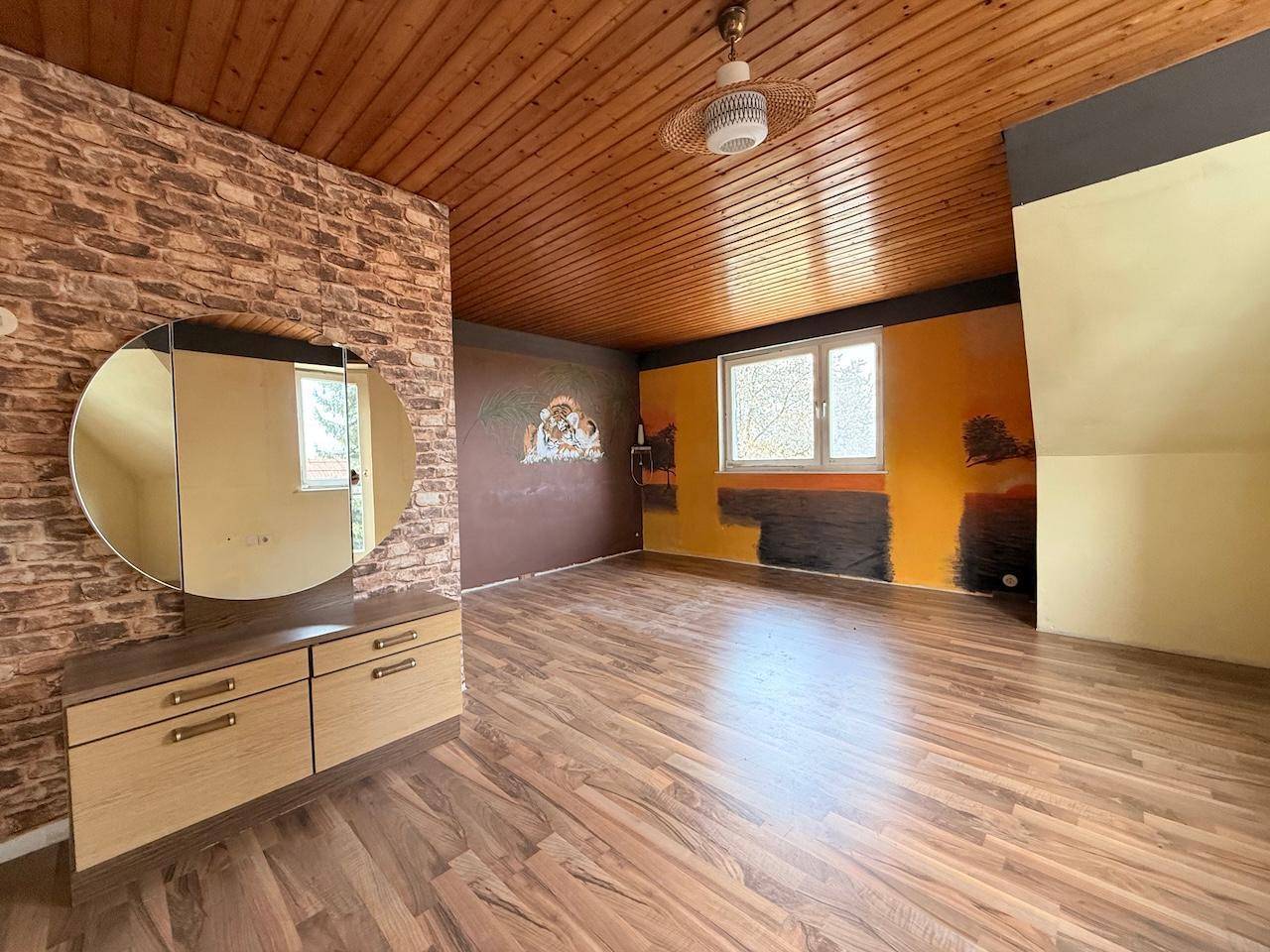 Geräumiges Zimmer mit Holzdecke, Laminatboden und farbigen Wänden, inklusive Schminktisch.