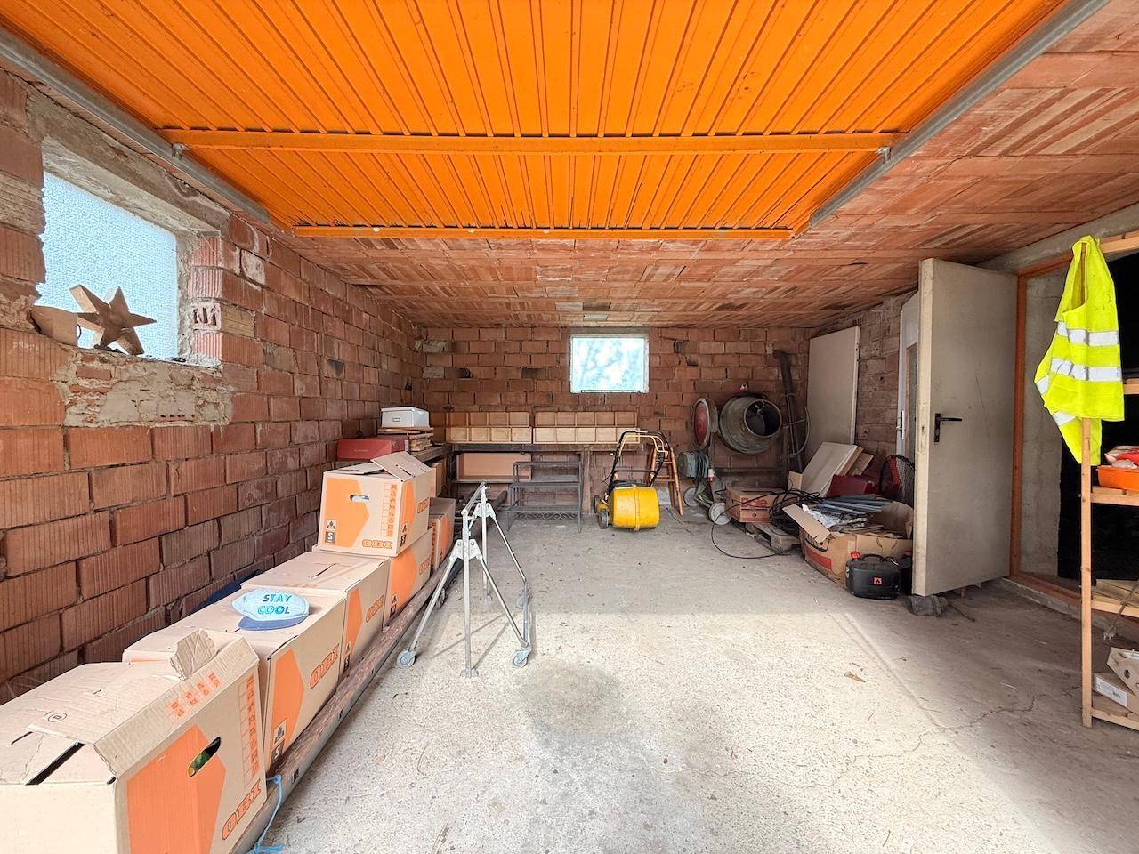 Geräumige Werkstatt mit unverputzten Ziegelwänden und Betonboden, ideal für Heimwerker.
