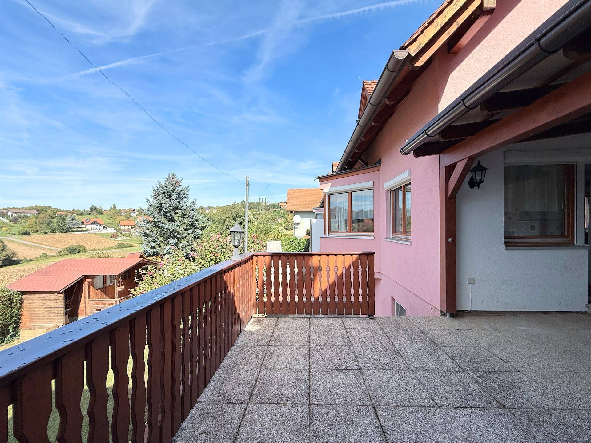 Große Terrasse mit Holzbalkon und weitem Blick über die Landschaft.