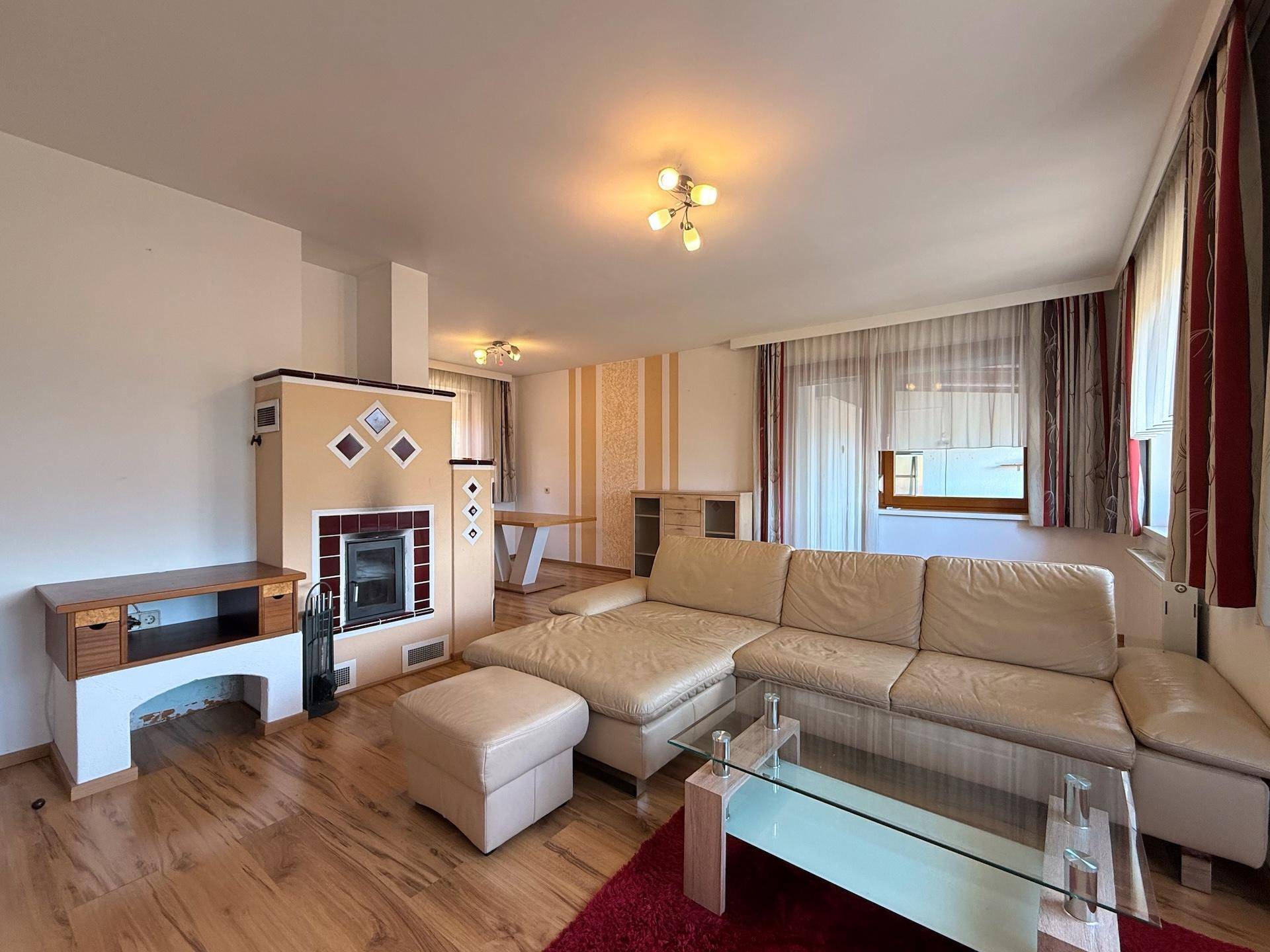 Gemütlicher Wohnbereich mit großem Ecksofa, Couchtisch und traditionellem Kachelofen.