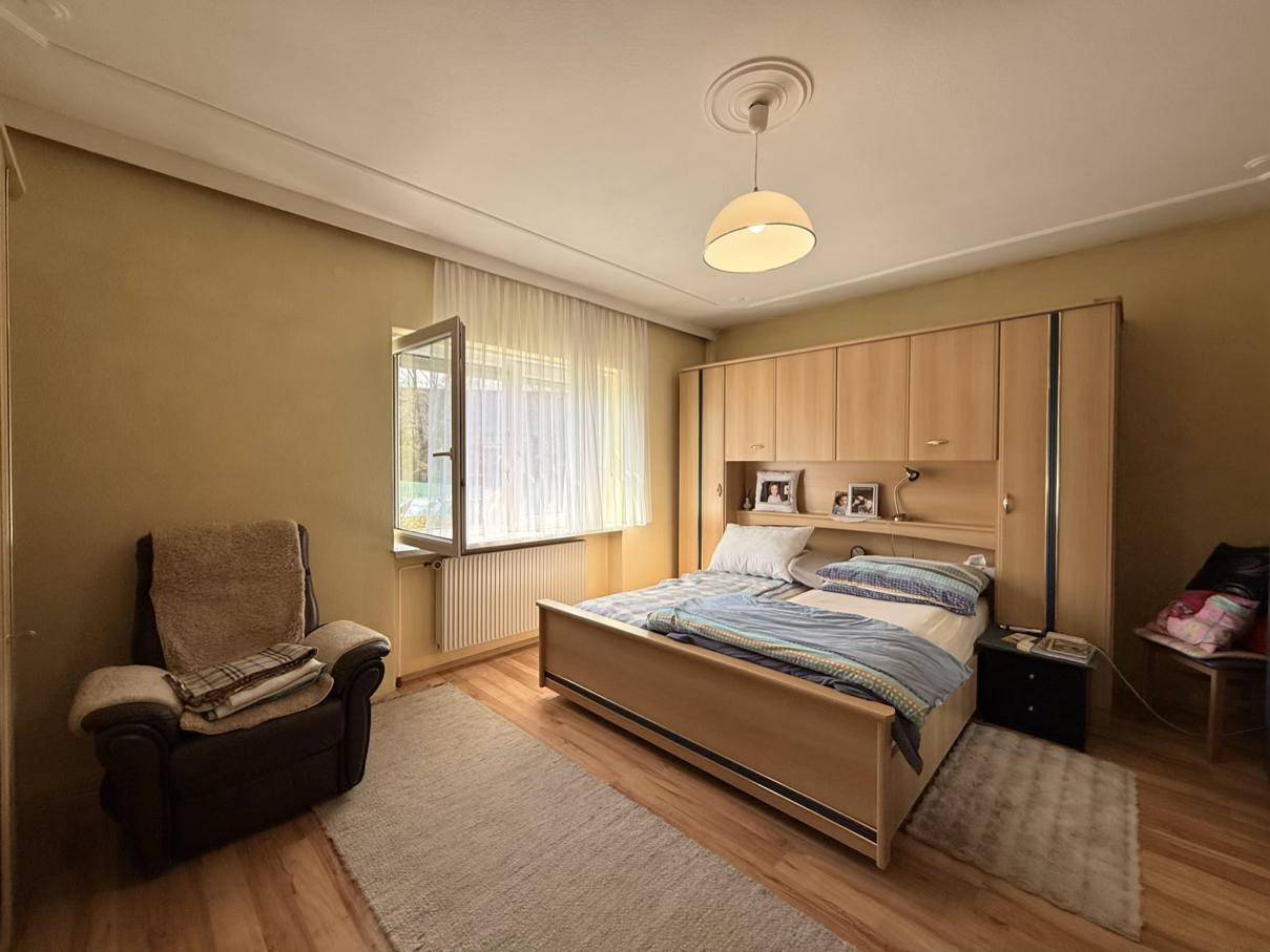 Schlafzimmer mit Doppelbett, Einbauschrank und einem Fenster, das Tageslicht hereinlässt.