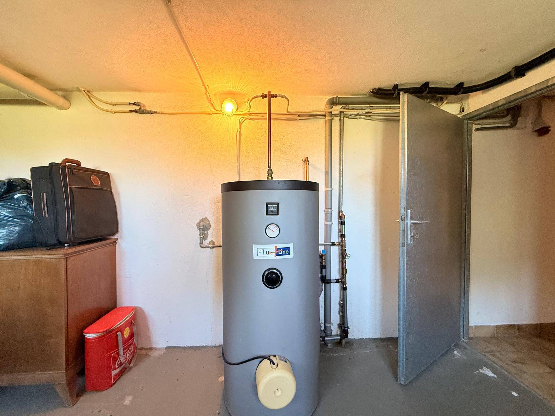 Kellerraum mit Warmwasserspeicher und Installationen, bereit für den Gebrauch.