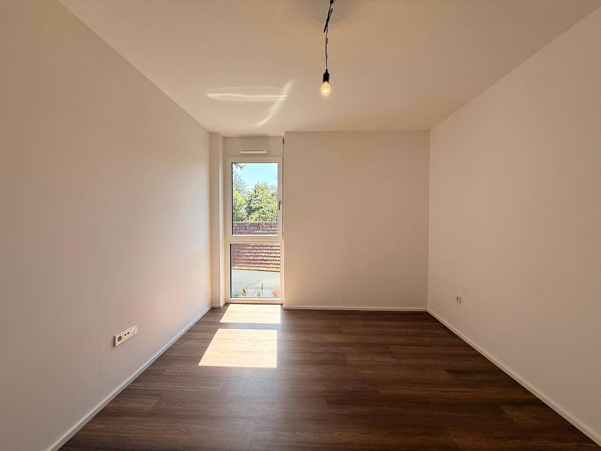 Geräumiges Schlafzimmer mit viel Tageslicht und Blick ins Grüne.